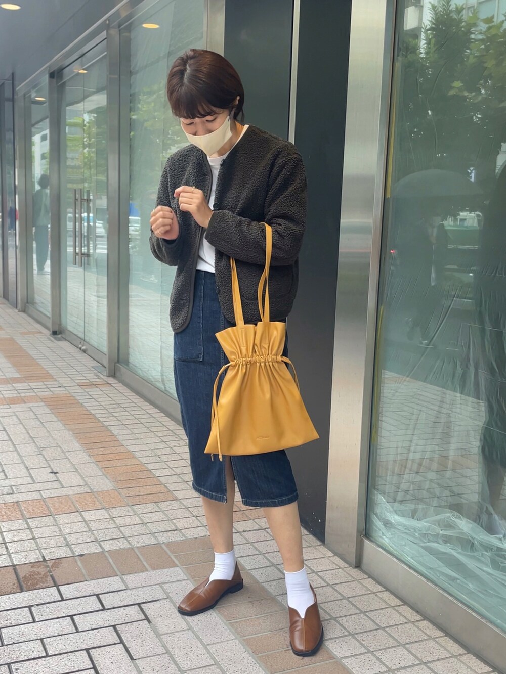 イエロー系のトートバッグ、グリーン系のその他アウター、ブラウン系のシューズを着用したレディースの秋コーディネートの2枚目の写真