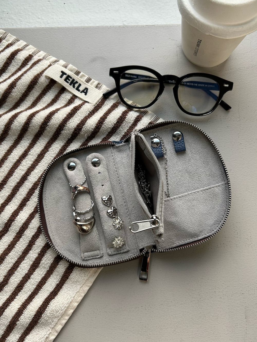 ブルー系のポーチ、シルバー系のネックレスを着用したレディースの秋コーディネートの2枚目の写真