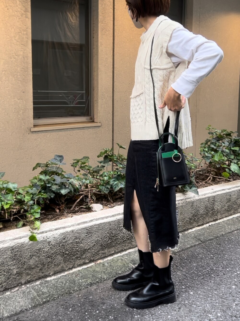 ブラック系のショルダーバッグ、ブラック系のデニムスカート、ブラック系のブーツを着用したレディースの秋コーディネートの3枚目の写真