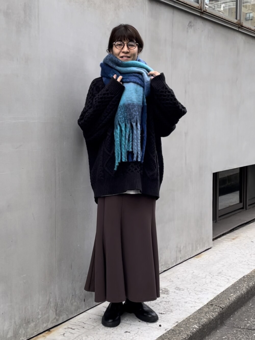 ブラック系のニット/セーター、ブラック系のブーツ、ブラウン系のスカートを着用したレディースの秋コーディネートの2枚目の写真