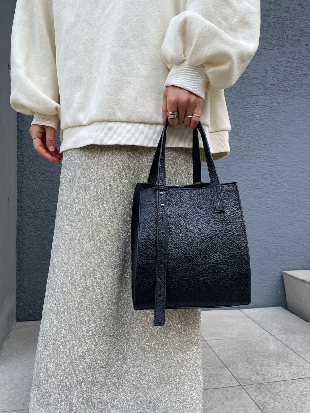 ブラック系のトートバッグ、ベージュ系のスカート、ブラック系のブーツを着用したレディースの冬コーディネートの2枚目の写真