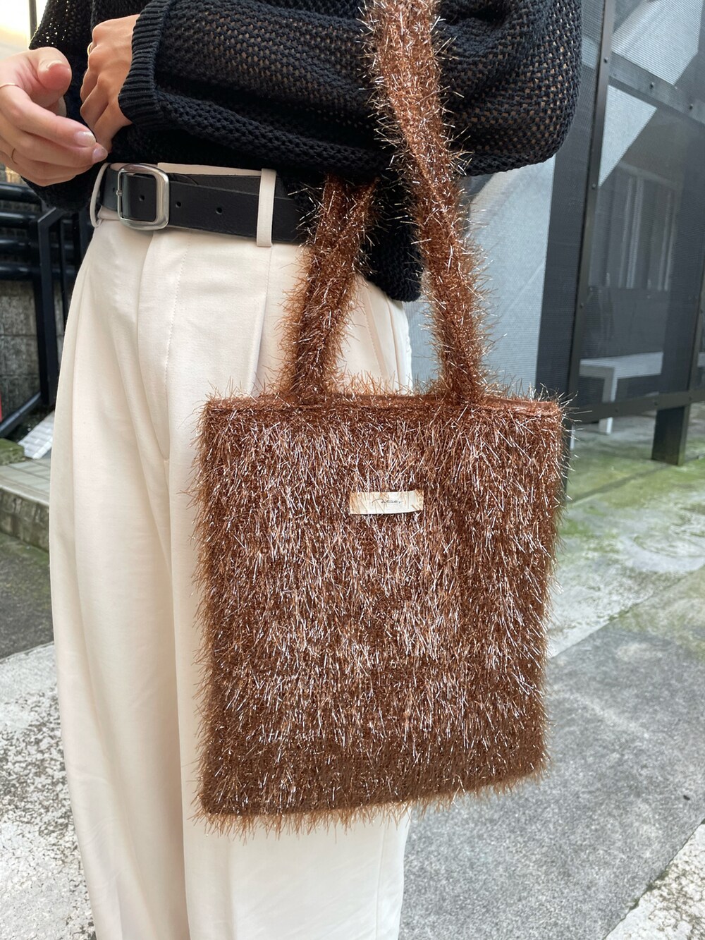 ブラウン系のトートバッグ、ホワイト系のパンツ、ブラック系のサンダルを着用したレディースの夏コーディネートの3枚目の写真