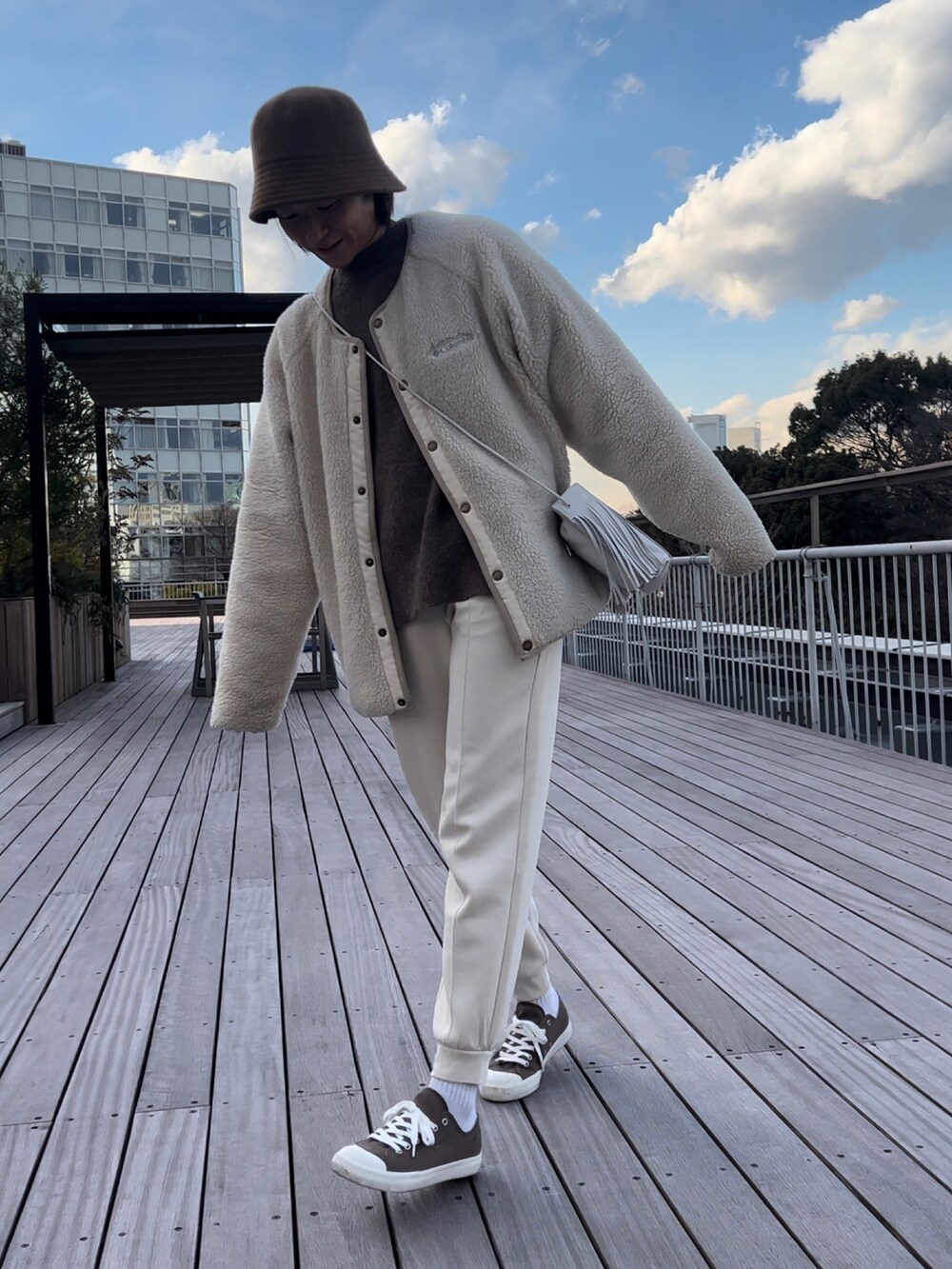 ホワイト系のショルダーバッグ、ホワイト系のブルゾン、ブラウン系のニット/セーターを着用したレディースの冬コーディネートの2枚目の写真