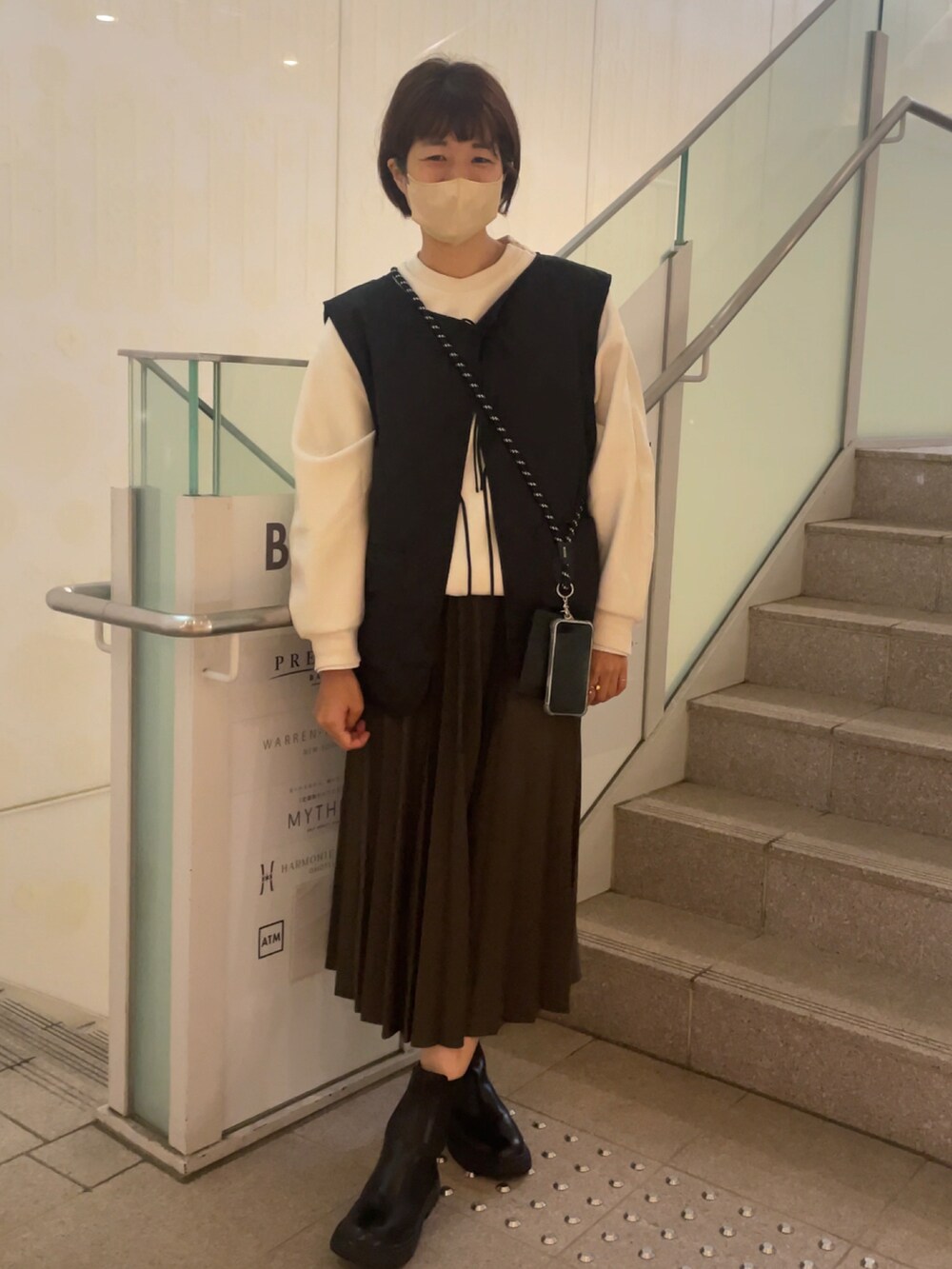 ブラック系のベスト、ホワイト系のスウェット、グリーン系のスカートを着用したレディースの秋コーディネートの2枚目の写真