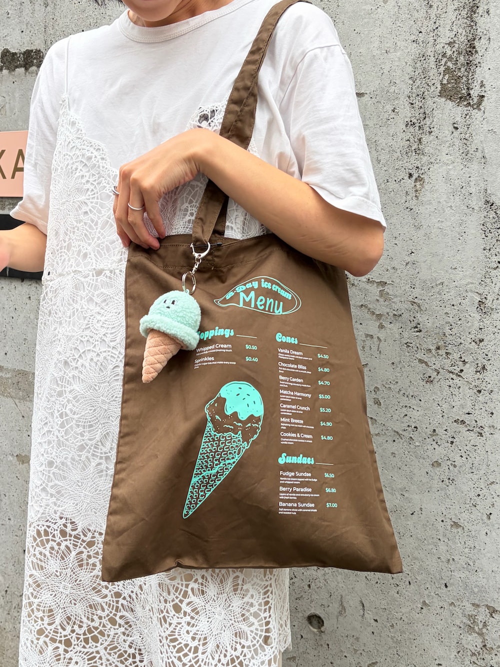 ブラウン系のトートバッグ、ホワイト系のTシャツ/カットソー、ベージュ系のキャップを着用したレディースの夏コーディネートの3枚目の写真