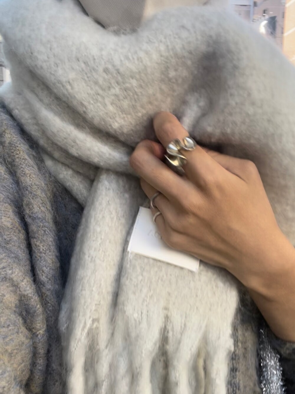 グレー系のカーディガン/ボレロ、ブラック系のスカート、ホワイト系のストール/ショールを着用したレディースの冬コーディネートの3枚目の写真