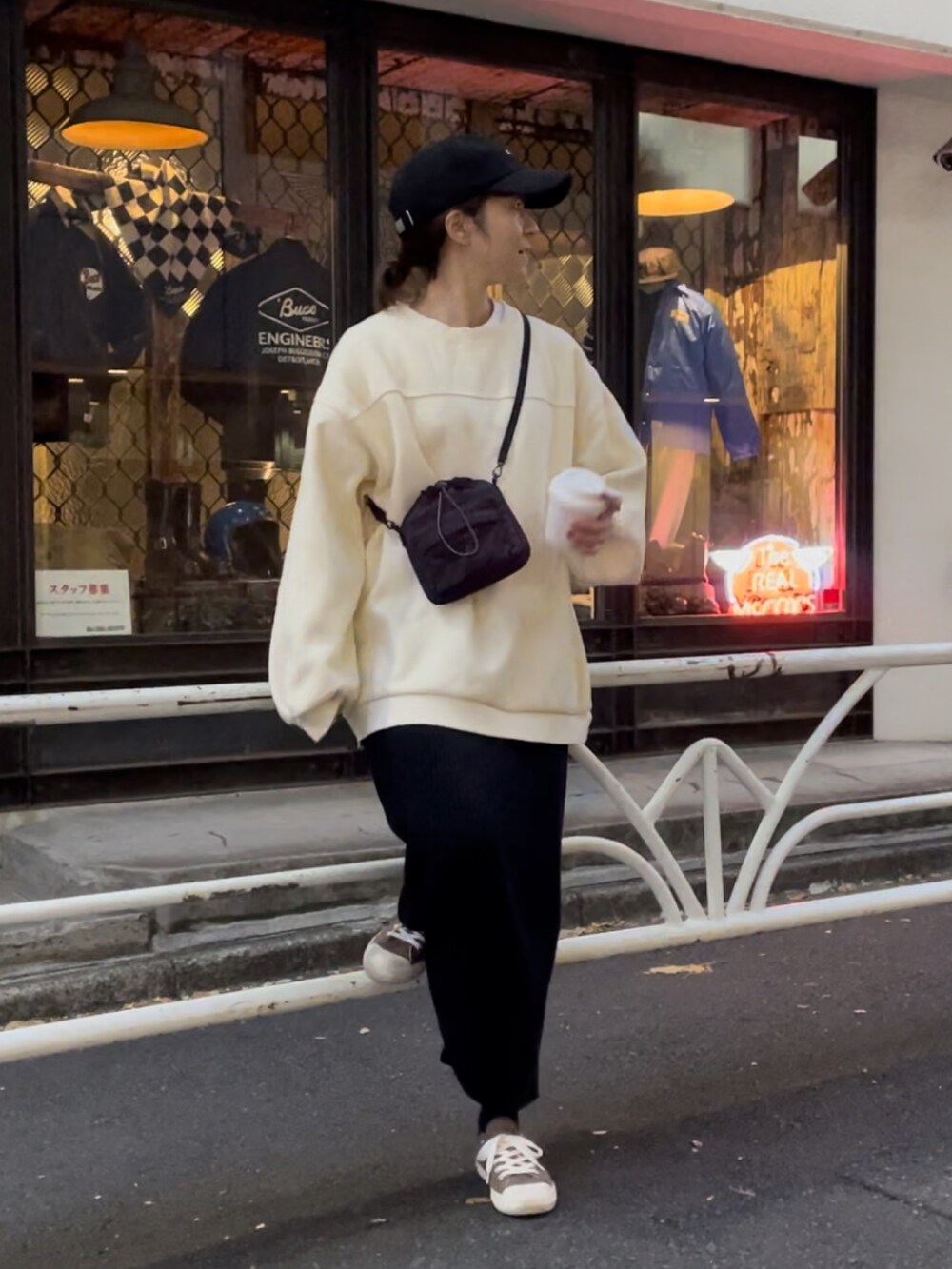 ブラック系のボディバッグ/ウエストポーチ、ホワイト系のスニーカー、ブラック系のスカートを着用したレディースの秋コーディネートの2枚目の写真