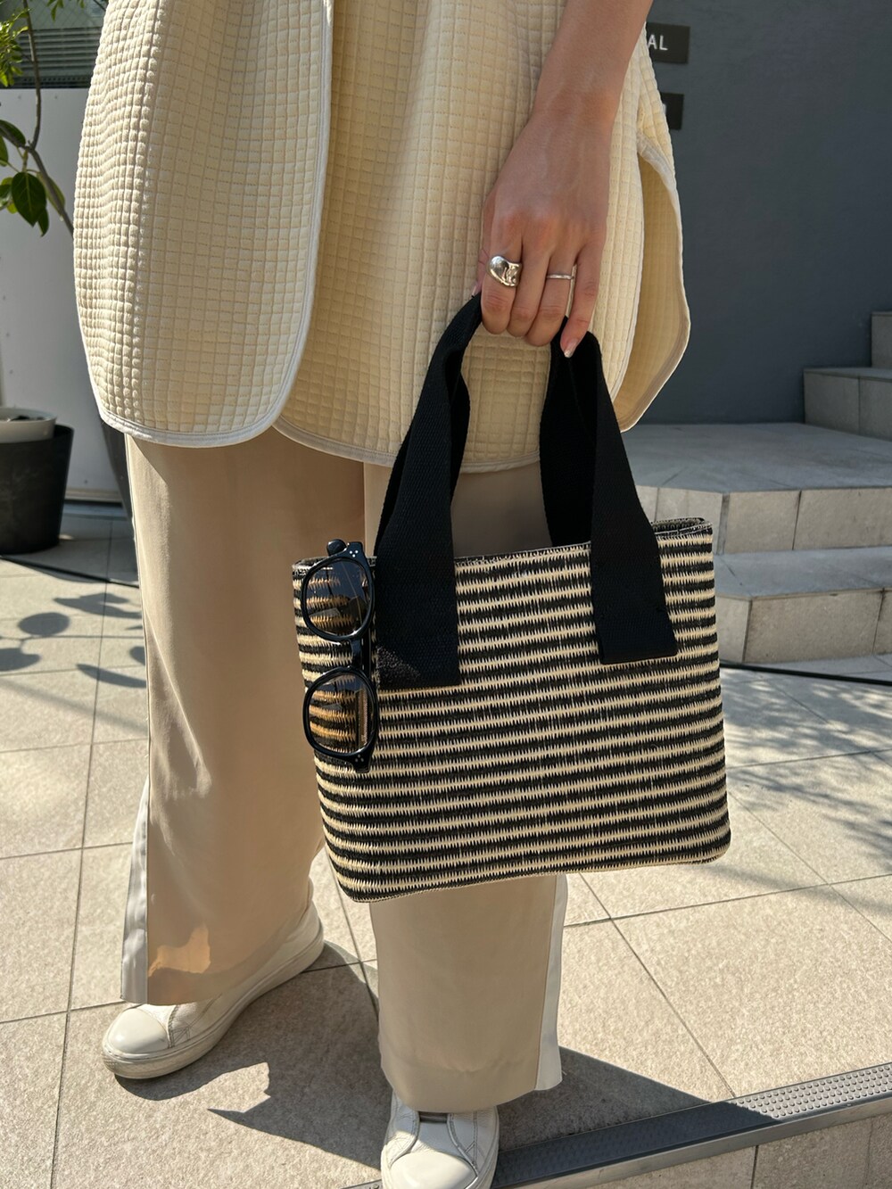 ベージュ系のベスト、ブラック系のトートバッグ、ベージュ系のその他パンツを着用したレディースの夏コーディネートの2枚目の写真