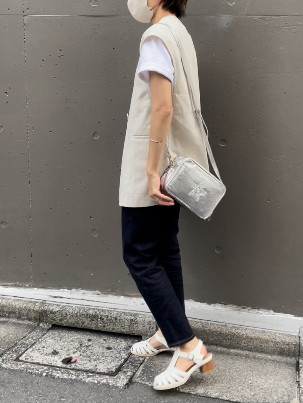 シルバー系のショルダーバッグ、ホワイト系のベスト、ホワイト系のTシャツ/カットソーを着用したレディースの夏コーディネートの3枚目の写真