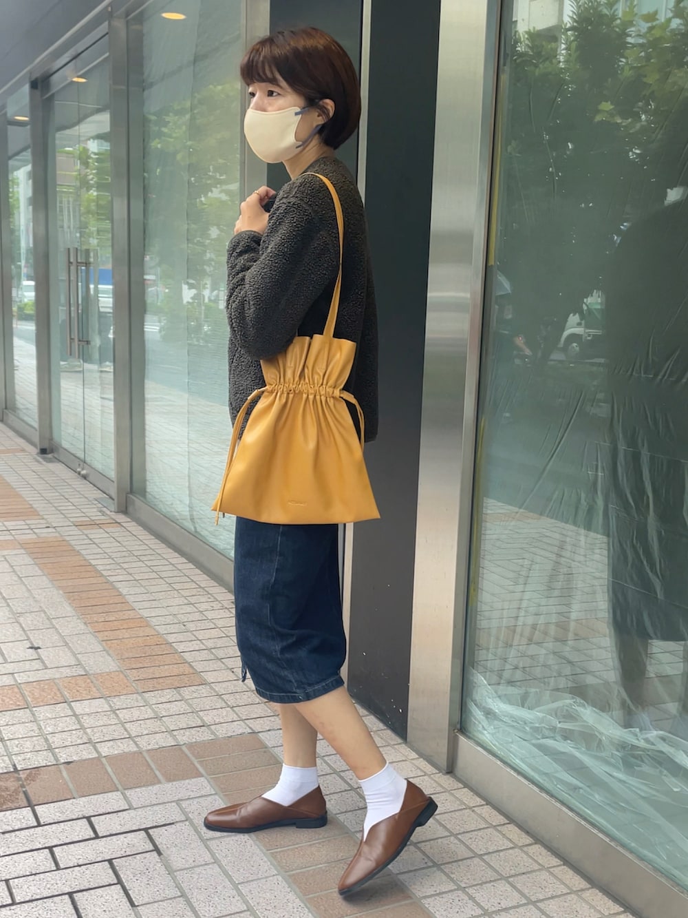 イエロー系のトートバッグ、グリーン系のその他アウター、ブラウン系のシューズを着用したレディースの秋コーディネートの3枚目の写真