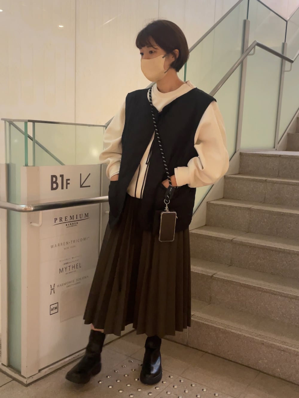 ブラック系のベスト、ホワイト系のスウェット、グリーン系のスカートを着用したレディースの秋コーディネートの3枚目の写真