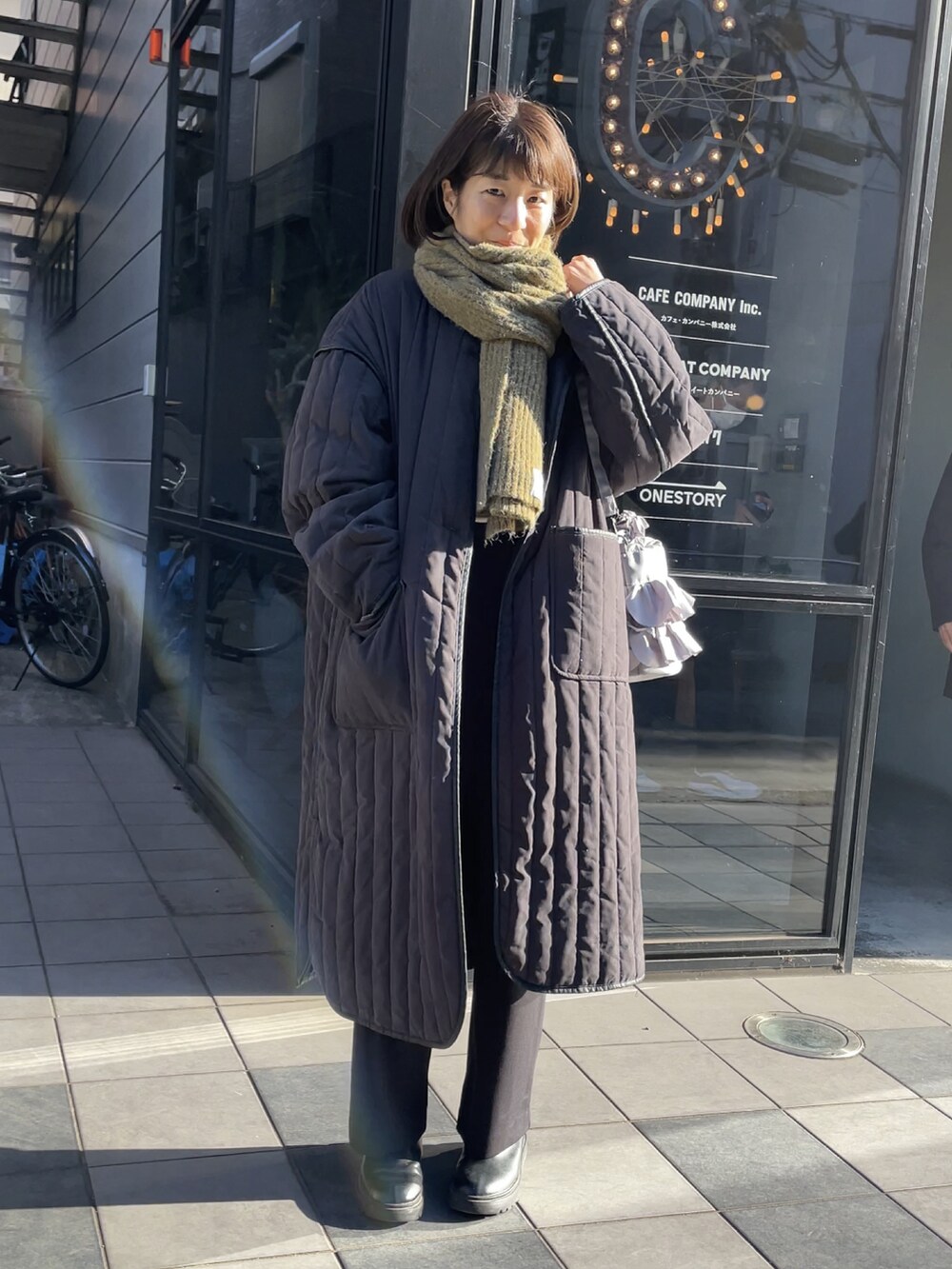 グレー系のショルダーバッグ、ブラック系のその他パンツ、ブラック系のダウンジャケット/コートを着用したレディースの冬コーディネートの2枚目の写真