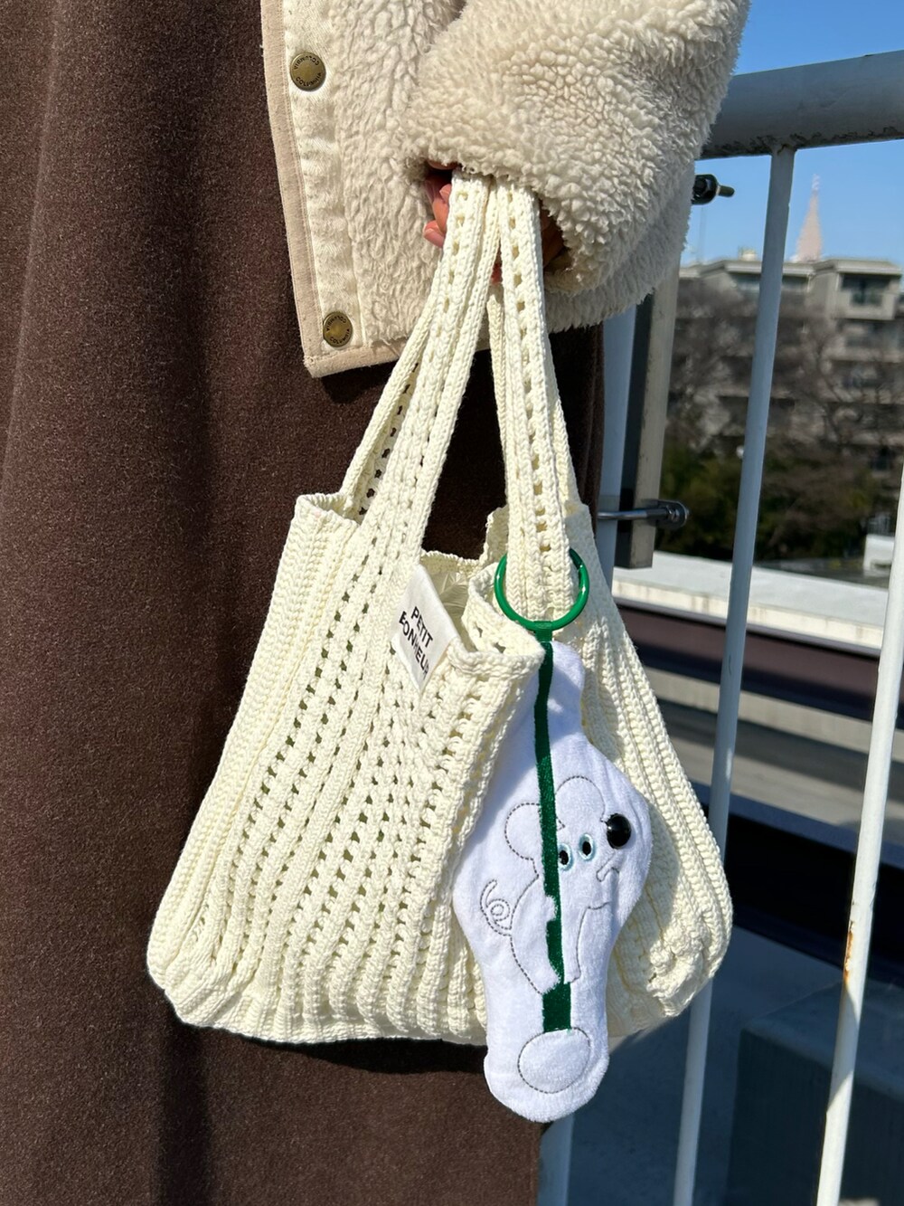 ホワイト系のハンドバッグ、ホワイト系のエコバッグ/サブバッグ、ブラウン系のワンピースを着用したレディースの冬コーディネートの2枚目の写真