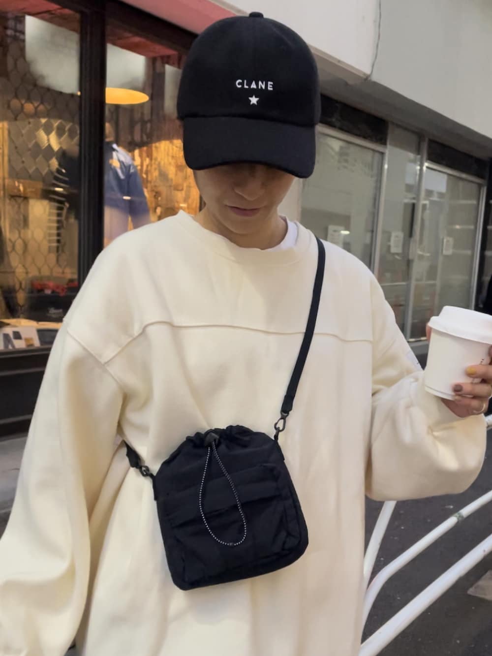 ブラック系のボディバッグ/ウエストポーチ、ホワイト系のスニーカー、ブラック系のスカートを着用したレディースの秋コーディネートの3枚目の写真