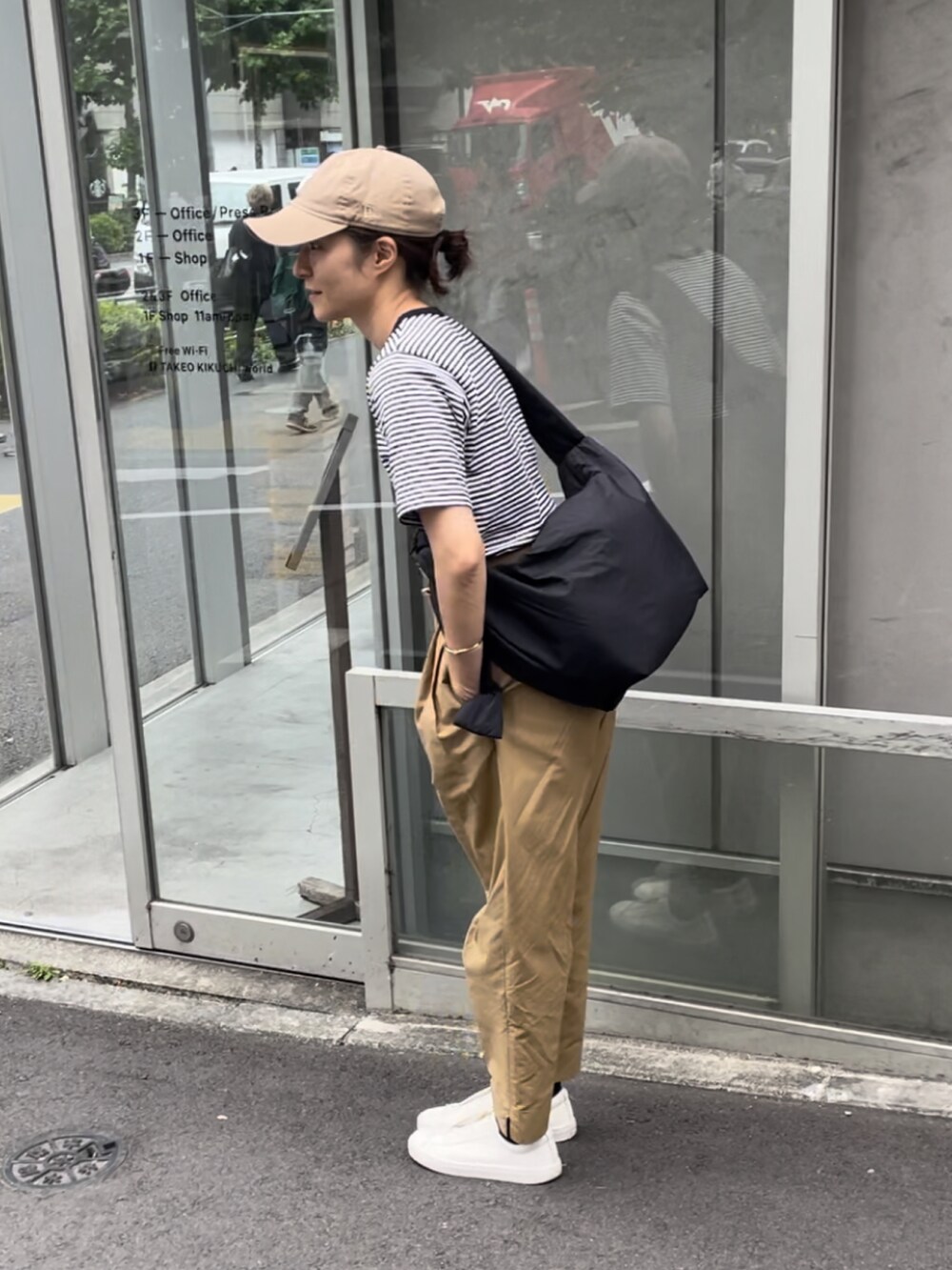 ブラック系のショルダーバッグ、ブラック系のTシャツ/カットソー、ベージュ系のチノパンツを着用したレディースの夏コーディネートの2枚目の写真