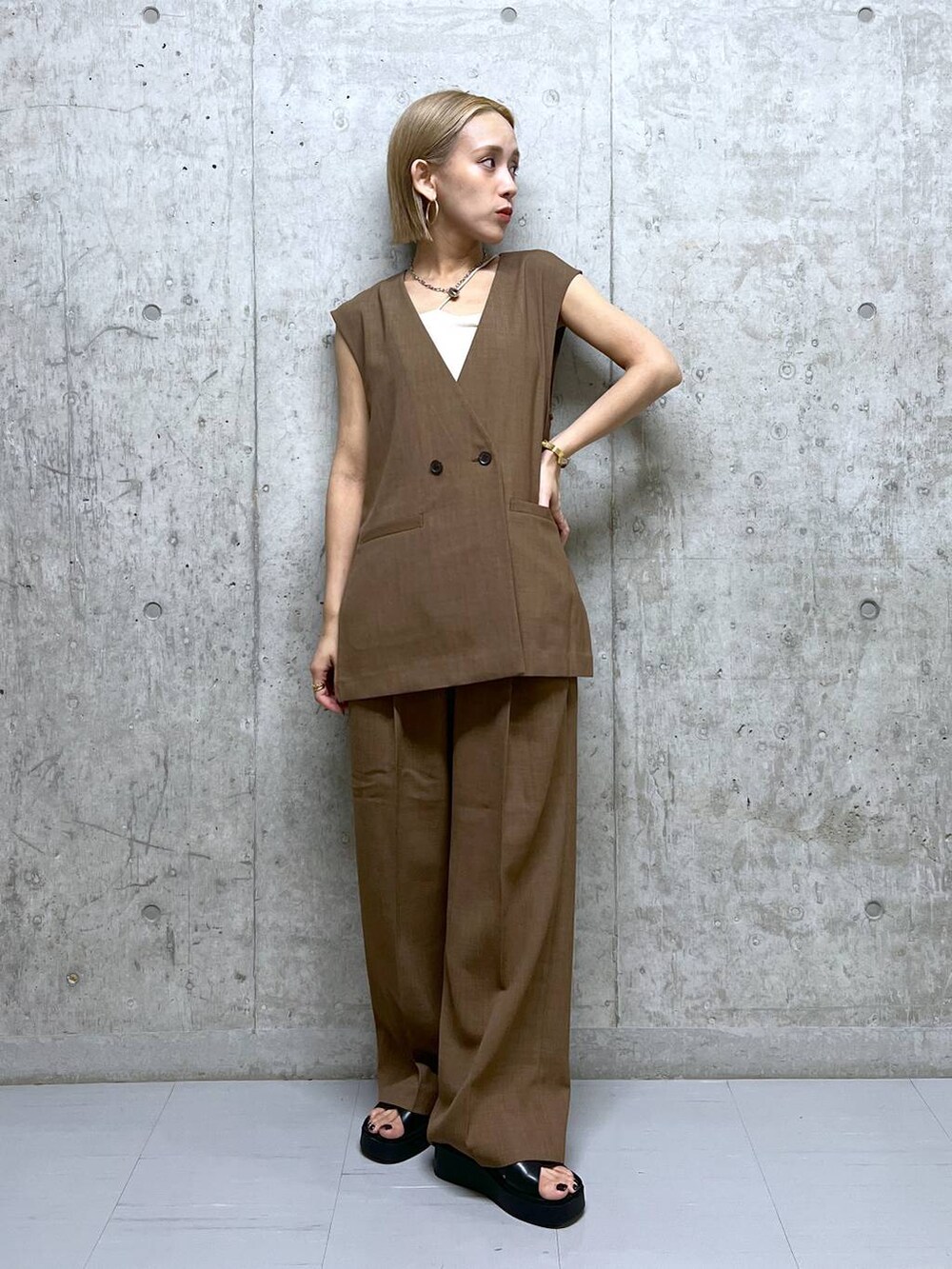 ブラウン系のベスト、ブラウン系のスラックス、ブラック系のサンダルを着用したレディースの夏コーディネートの4枚目の写真