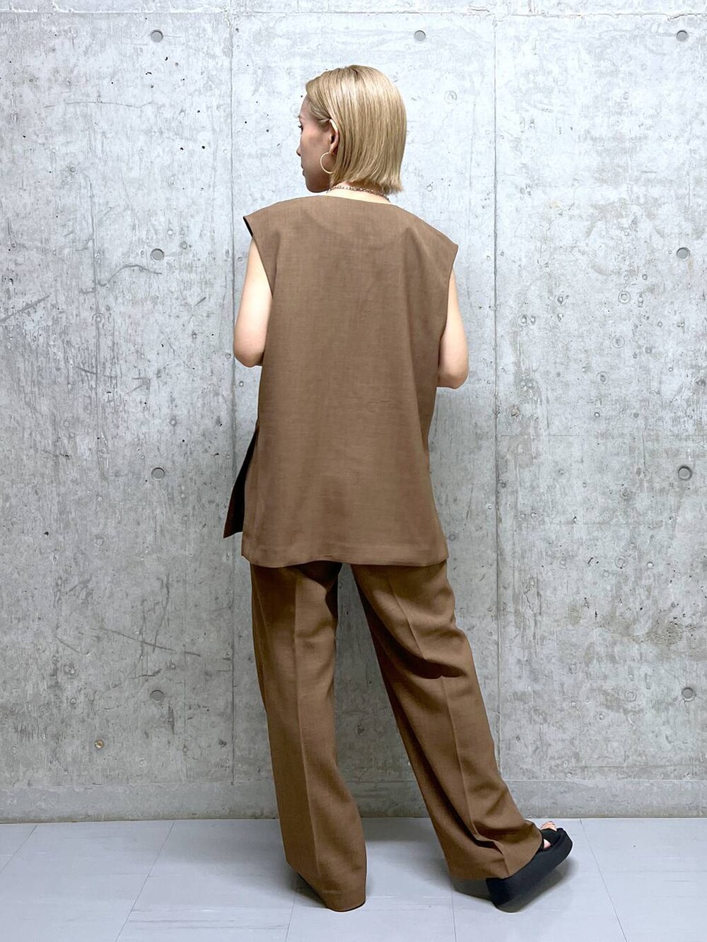 ブラウン系のベスト、ブラウン系のスラックス、ブラック系のサンダルを着用したレディースの夏コーディネートの3枚目の写真