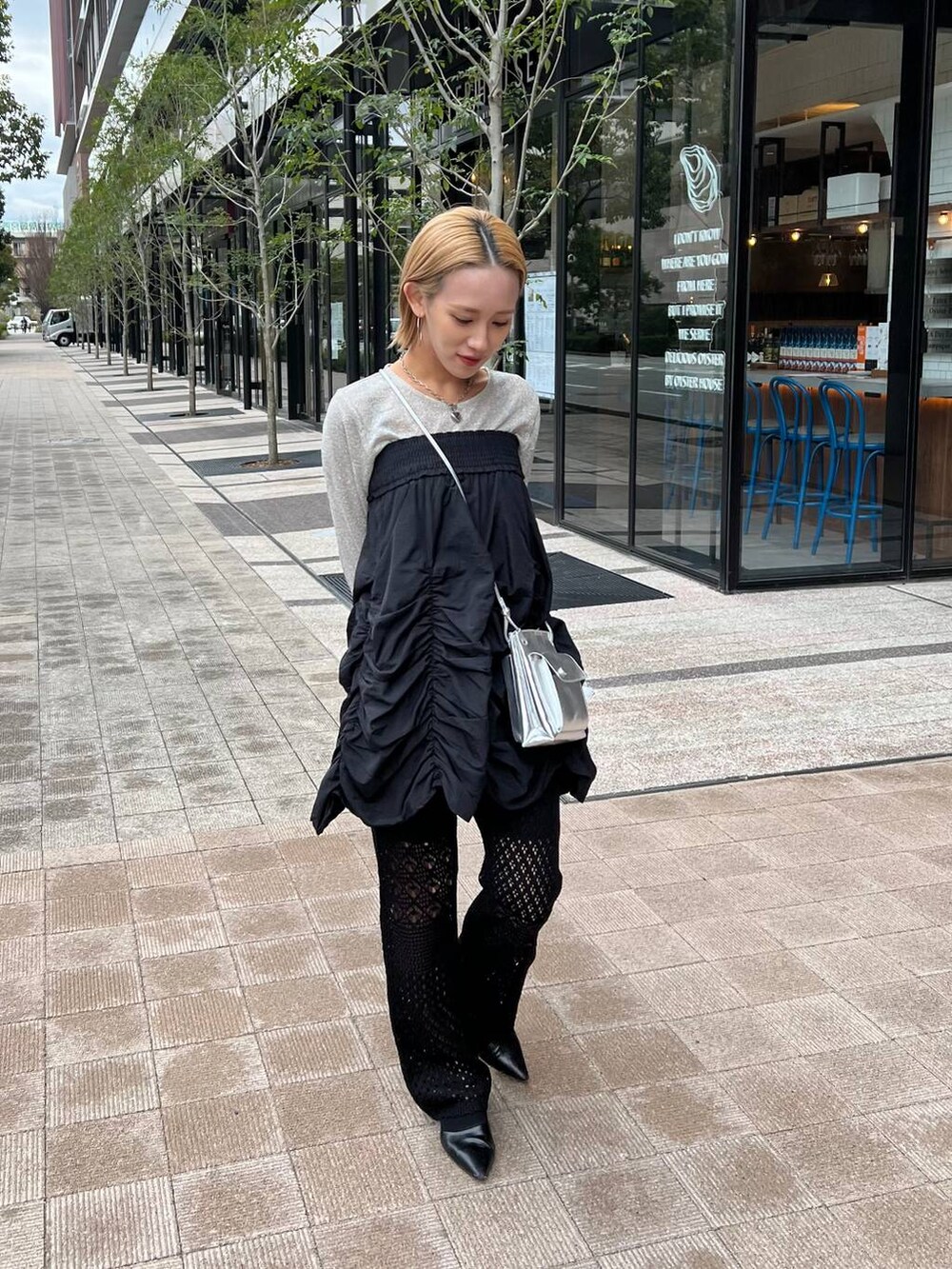 ブラック系のスカート、シルバー系のショルダーバッグ、ブラック系のパンプスを着用したレディースの春コーディネートの6枚目の写真