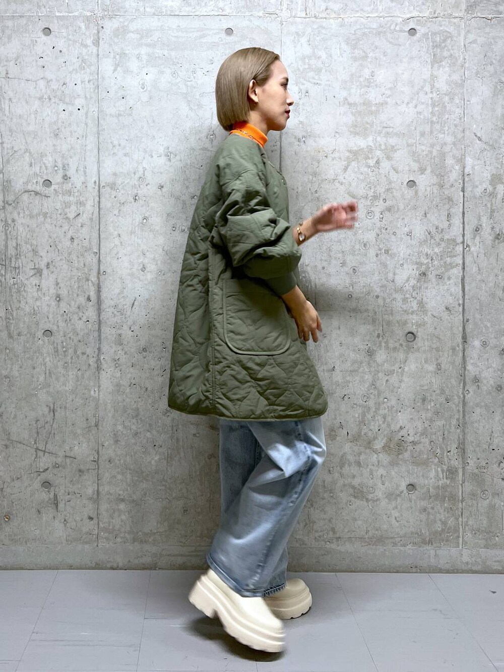 ブルー系のデニムパンツ、オレンジ系のニット/セーター、グリーン系のブルゾンを着用したレディースの冬コーディネートの3枚目の写真