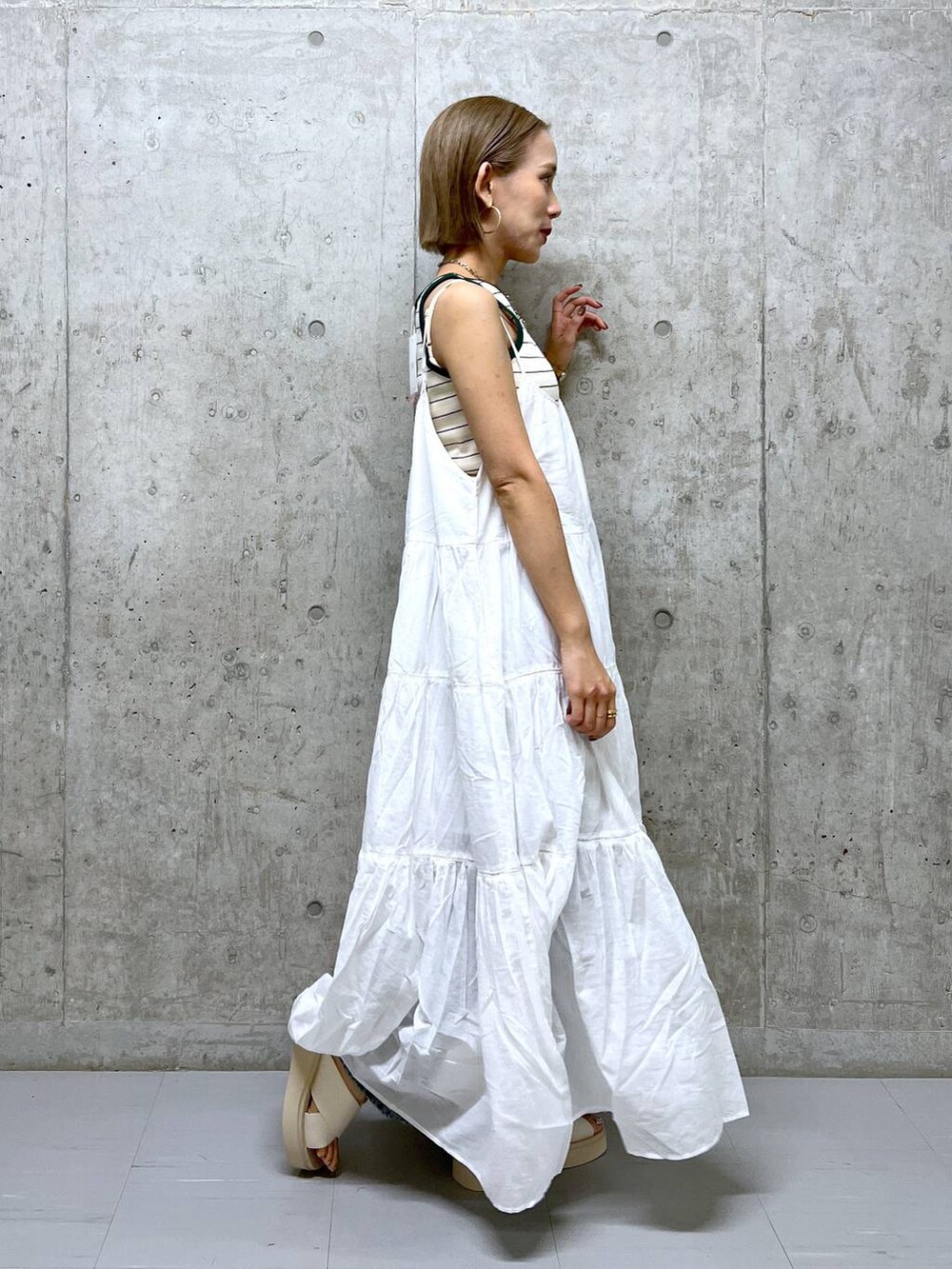 ベージュ系のタンクトップ、ホワイト系のワンピース、ホワイト系のサンダルを着用したレディースの夏コーディネートの3枚目の写真