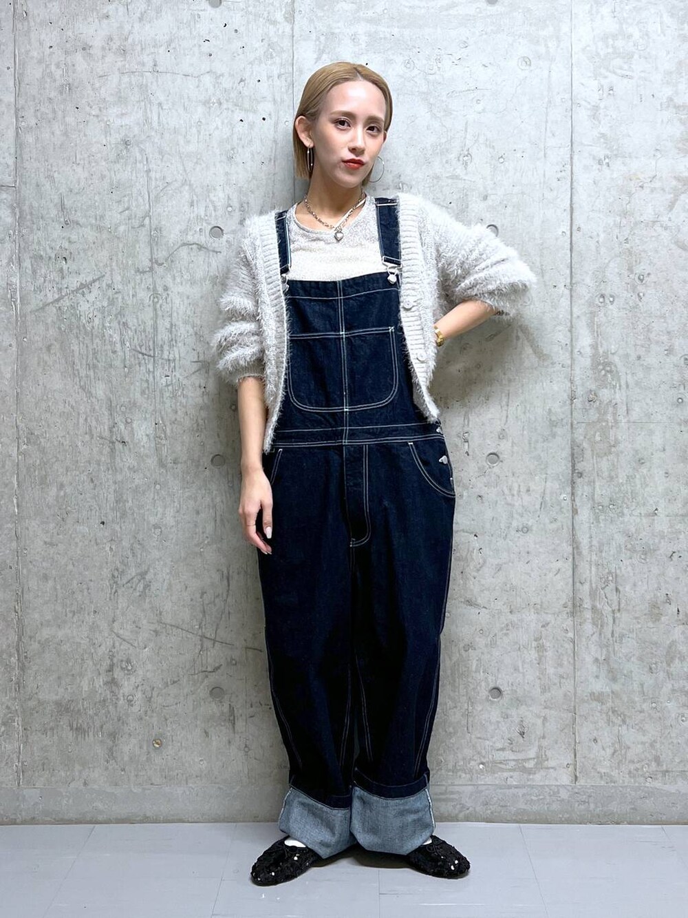 グレー系のニット/セーター、ホワイト系のTシャツ/カットソー、ブルー系のサロペット/オーバーオールを着用したレディースの冬コーディネートの3枚目の写真