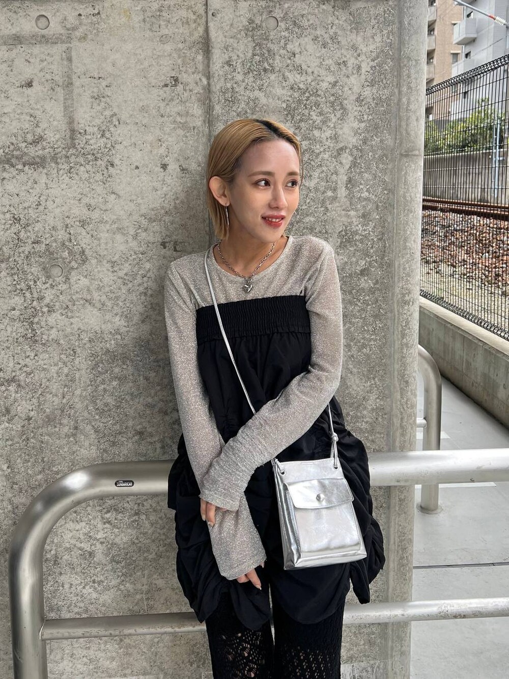 ブラック系のスカート、シルバー系のショルダーバッグ、ブラック系のパンプスを着用したレディースの春コーディネートの2枚目の写真