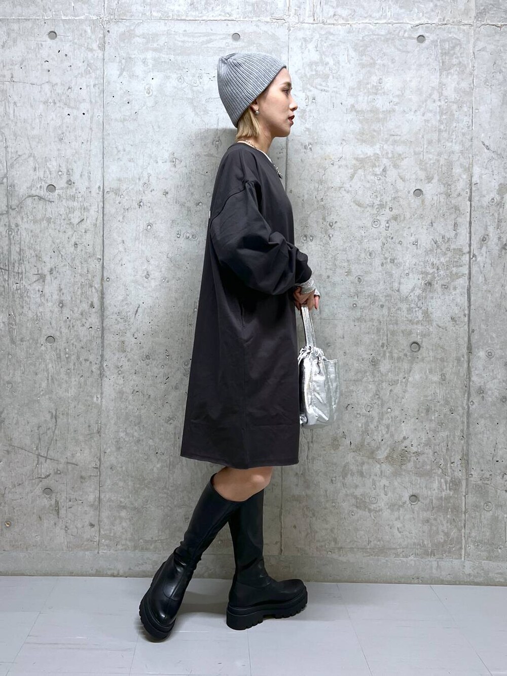 グレー系のワンピース、ブラック系のブーツ、ホワイト系のTシャツ/カットソーを着用したレディースの春コーディネートの3枚目の写真