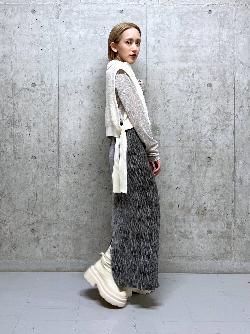 ホワイト系のブーツ、ホワイト系のTシャツ/カットソー、グレー系のスカートを着用したレディースの冬コーディネートの3枚目の写真