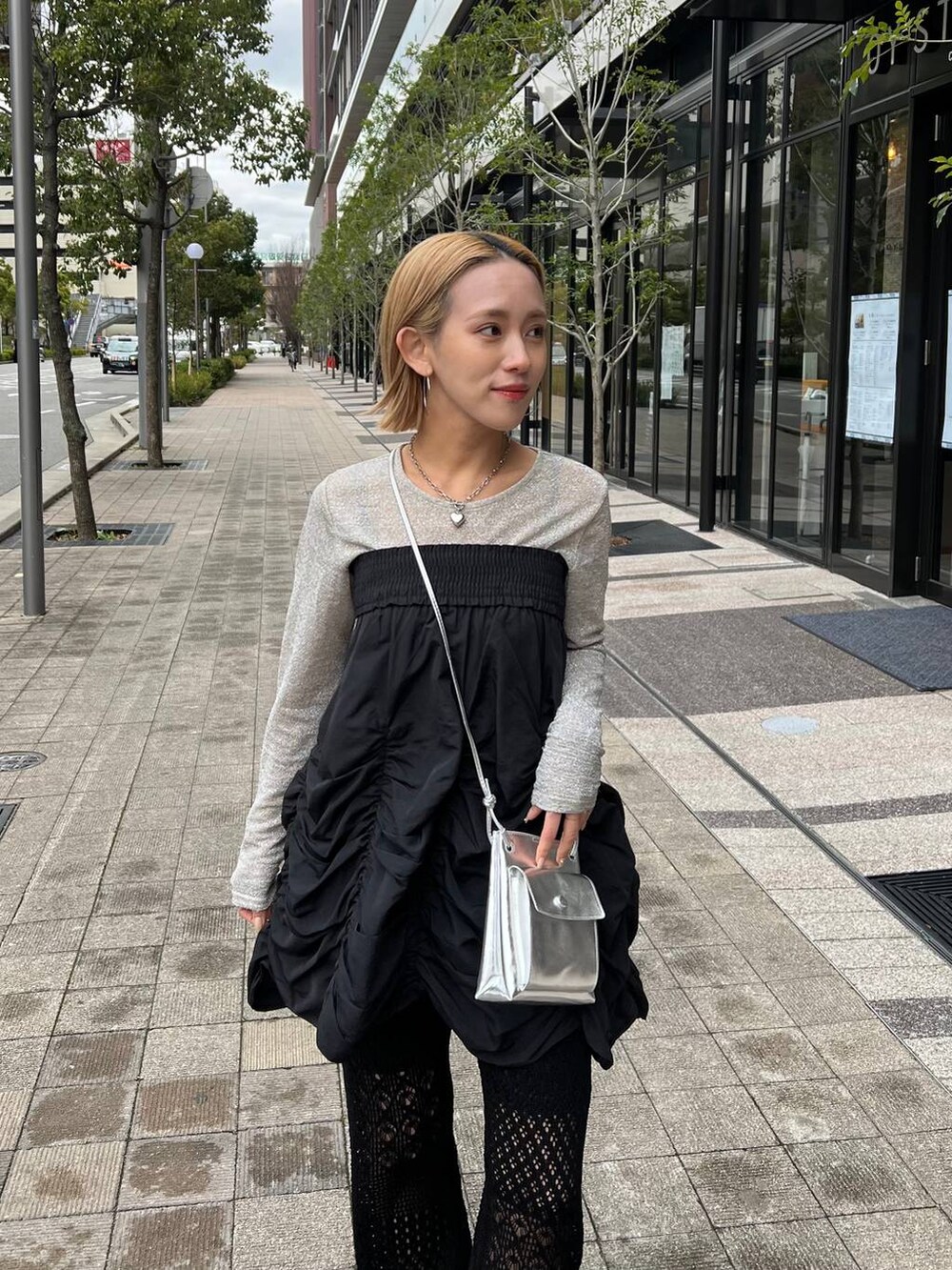 ブラック系のスカート、シルバー系のショルダーバッグ、ブラック系のパンプスを着用したレディースの春コーディネートの5枚目の写真