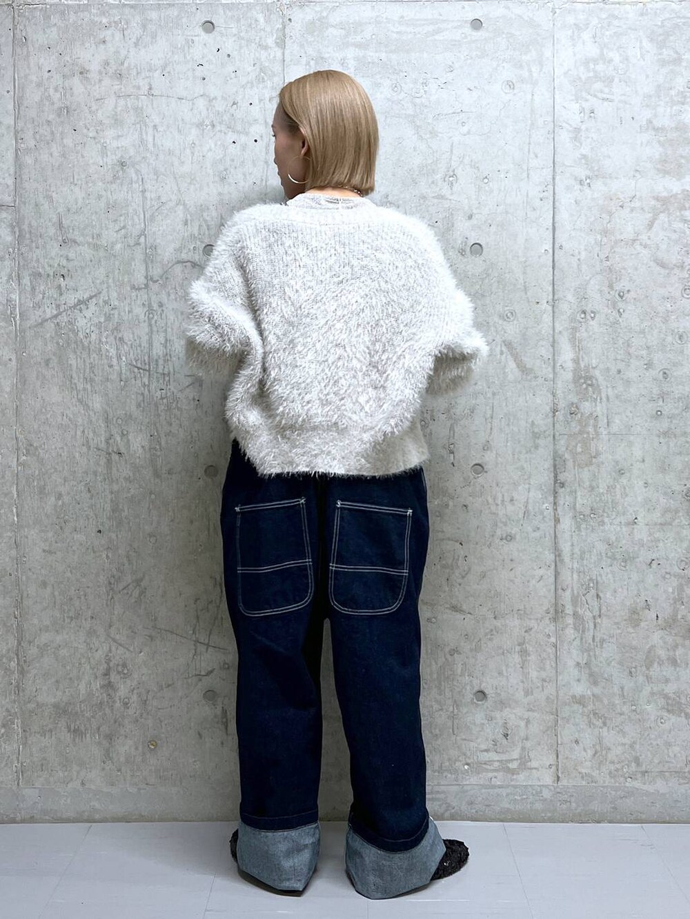 グレー系のニット/セーター、ホワイト系のTシャツ/カットソー、ブルー系のサロペット/オーバーオールを着用したレディースの冬コーディネートの4枚目の写真