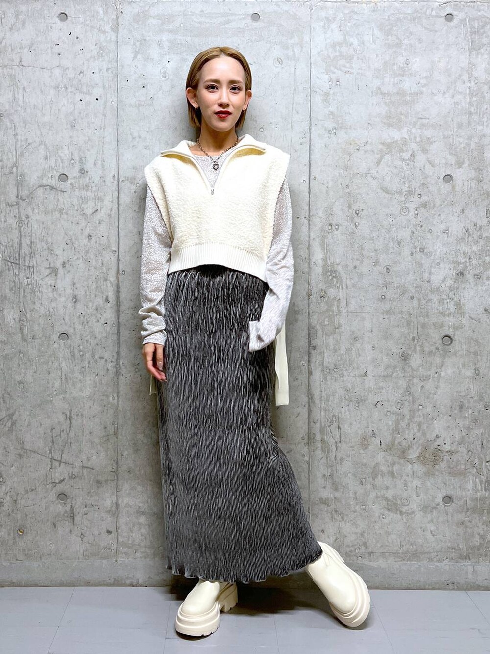 ホワイト系のブーツ、ホワイト系のTシャツ/カットソー、グレー系のスカートを着用したレディースの冬コーディネートの2枚目の写真