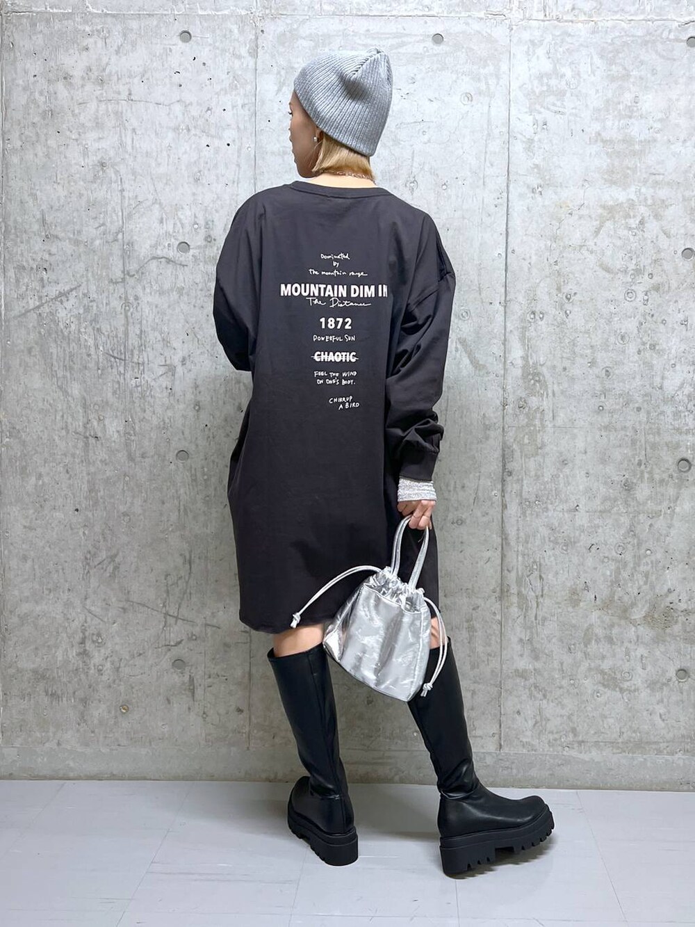 グレー系のワンピース、ブラック系のブーツ、ホワイト系のTシャツ/カットソーを着用したレディースの春コーディネートの4枚目の写真