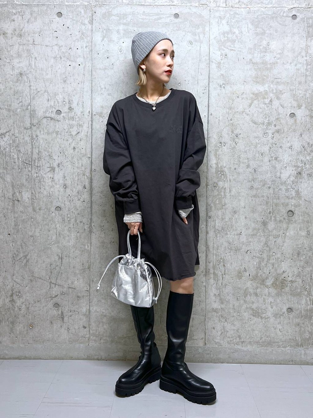 グレー系のワンピース、ブラック系のブーツ、ホワイト系のTシャツ/カットソーを着用したレディースの春コーディネートの2枚目の写真