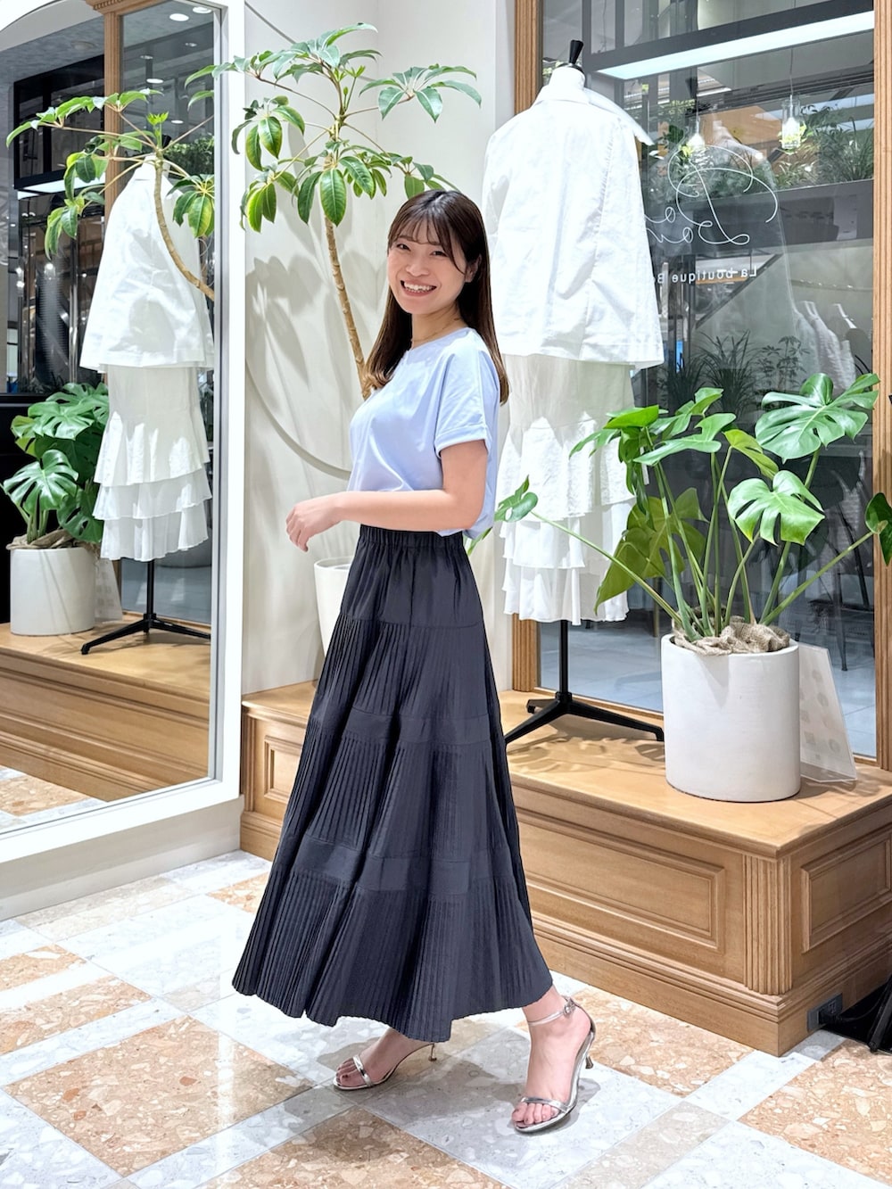 グレー系のスカート、シルバー系のハンドバッグ、ブルー系のTシャツ/カットソーを着用したレディースの春コーディネートの2枚目の写真