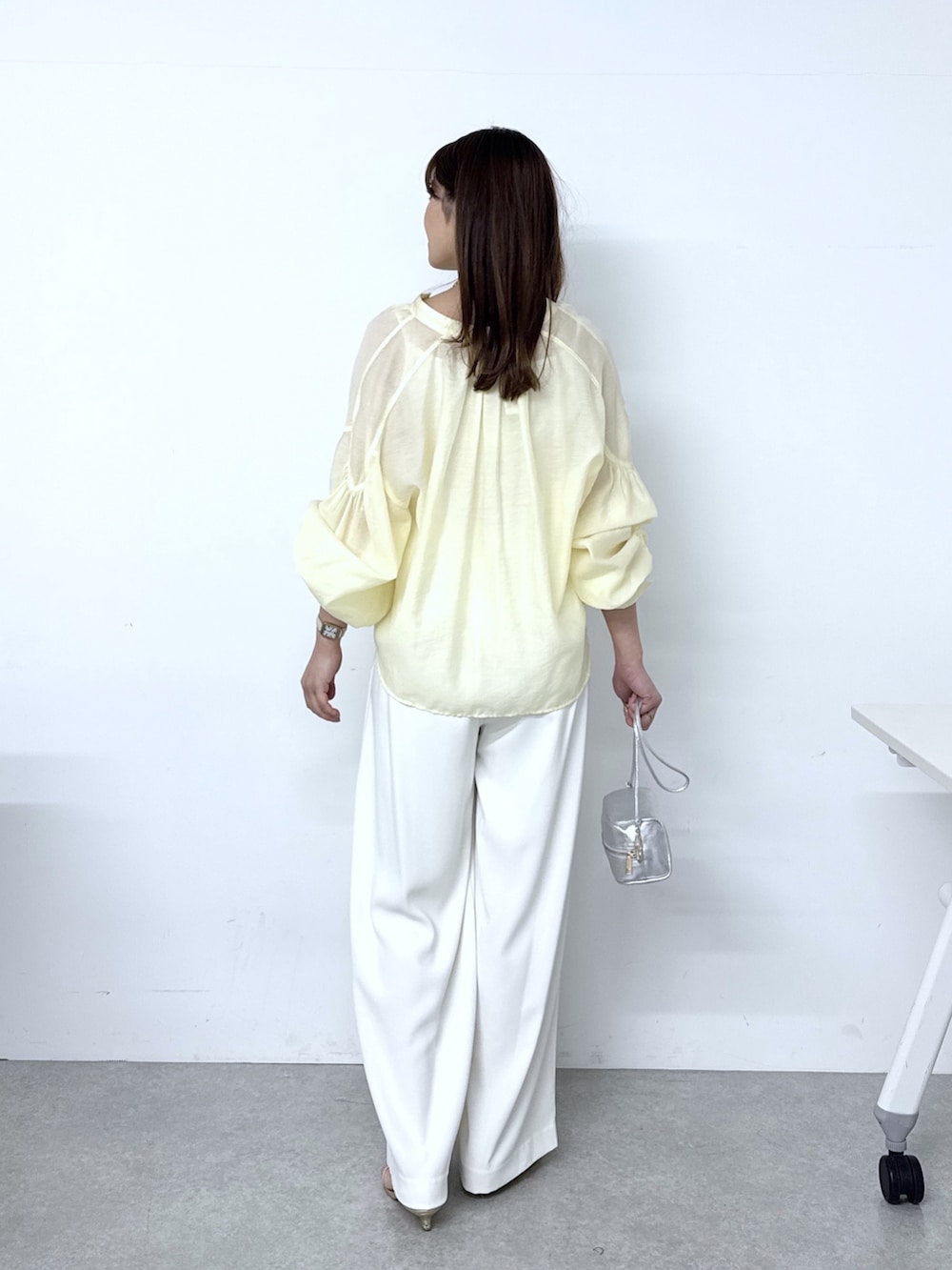 イエロー系のシャツ/ブラウス、ホワイト系のスラックス、シルバー系のトートバッグを着用したレディースの春コーディネートの3枚目の写真