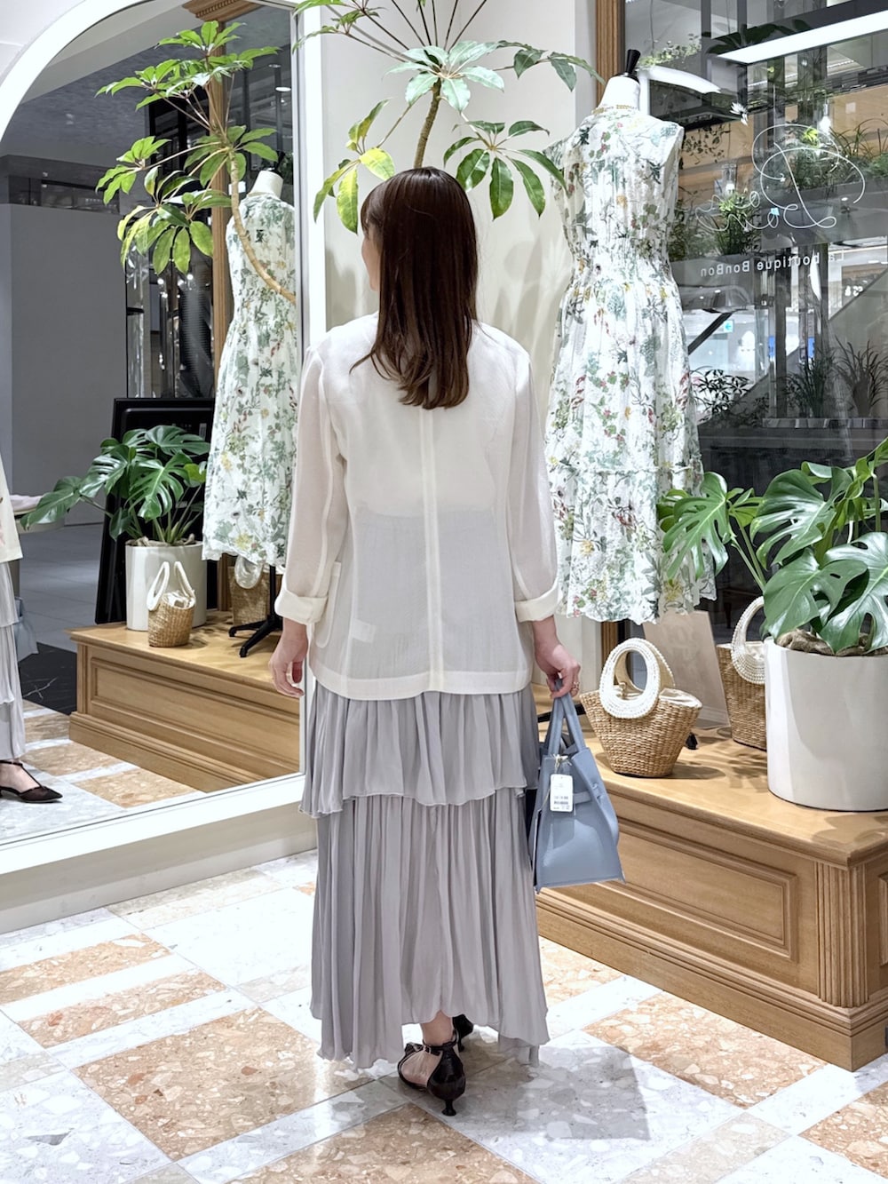 ホワイト系のテーラードジャケット、ホワイト系のニット/セーター、グレー系のスカートを着用したレディースの春コーディネートの3枚目の写真