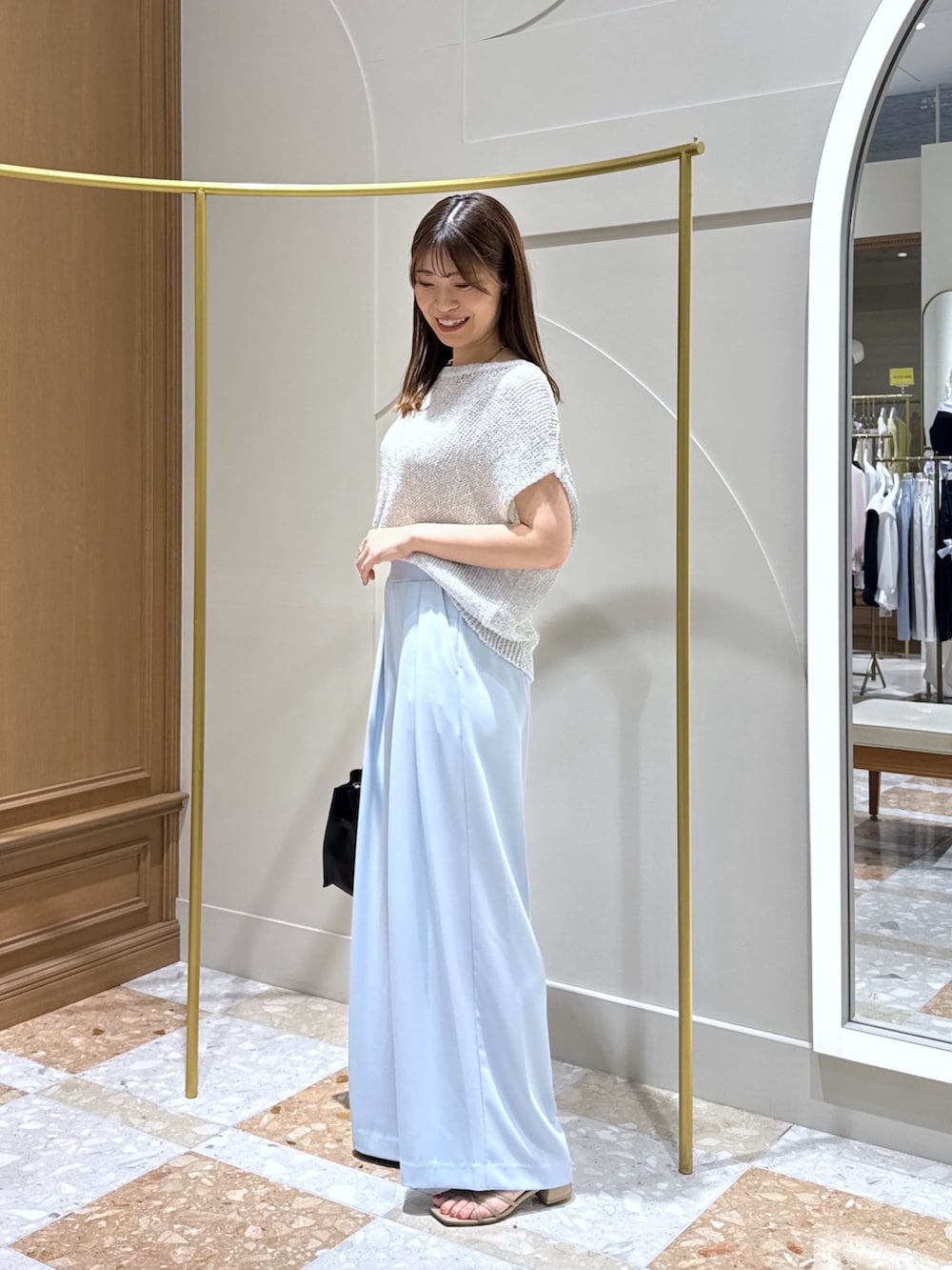 シルバー系のニット/セーター、ブルー系のスラックス、ブルー系のトートバッグを着用したレディースの夏コーディネートの2枚目の写真