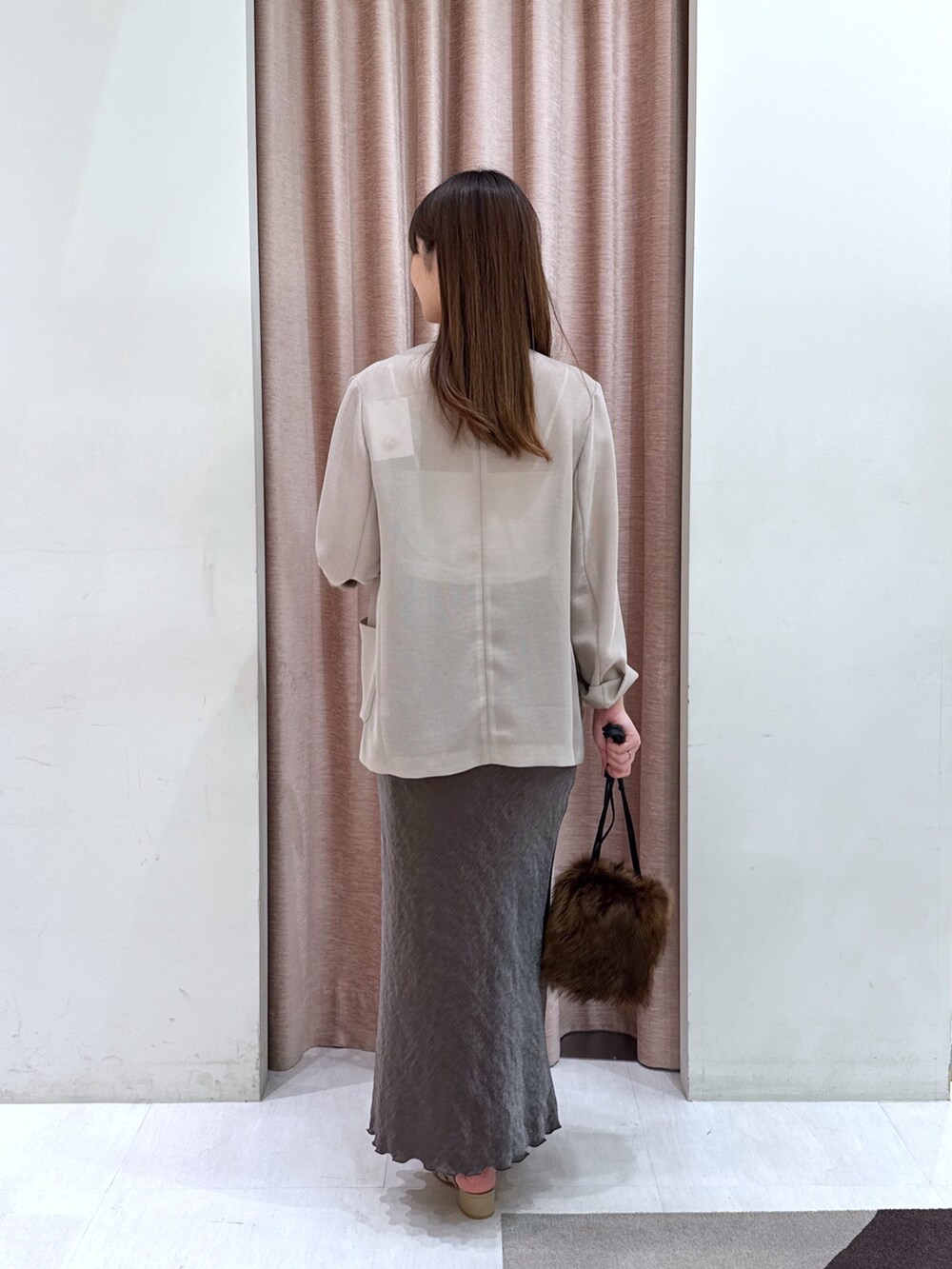 ベージュ系のテーラードジャケット、ホワイト系のキャミソール、ブラウン系のスカートを着用したレディースの秋コーディネートの3枚目の写真