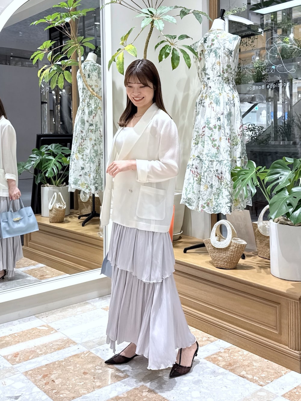 ホワイト系のテーラードジャケット、ホワイト系のニット/セーター、グレー系のスカートを着用したレディースの春コーディネートの2枚目の写真