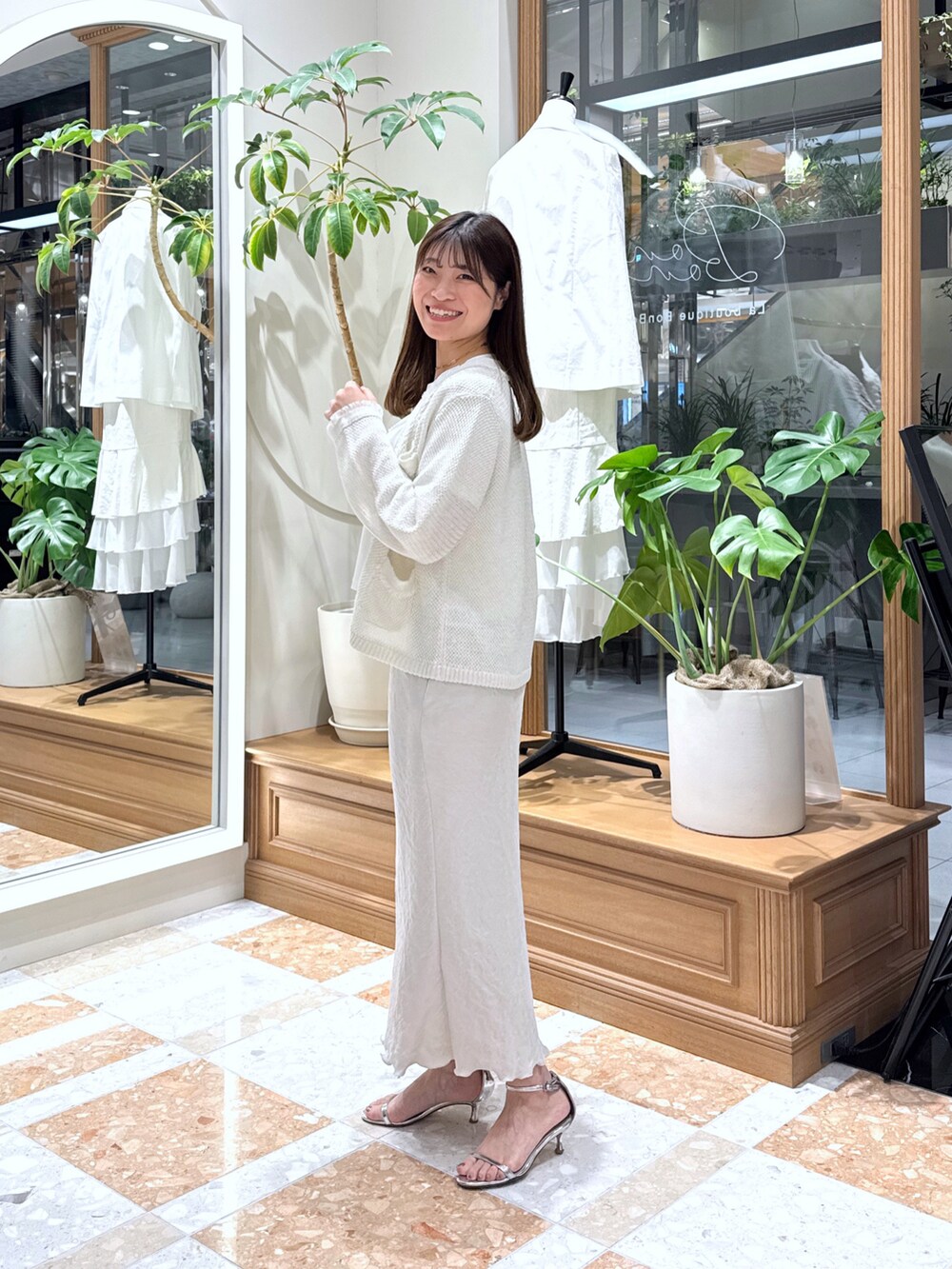 グレー系のスカート、シルバー系のハンドバッグ、ホワイト系のカーディガン/ボレロを着用したレディースの春コーディネートの2枚目の写真