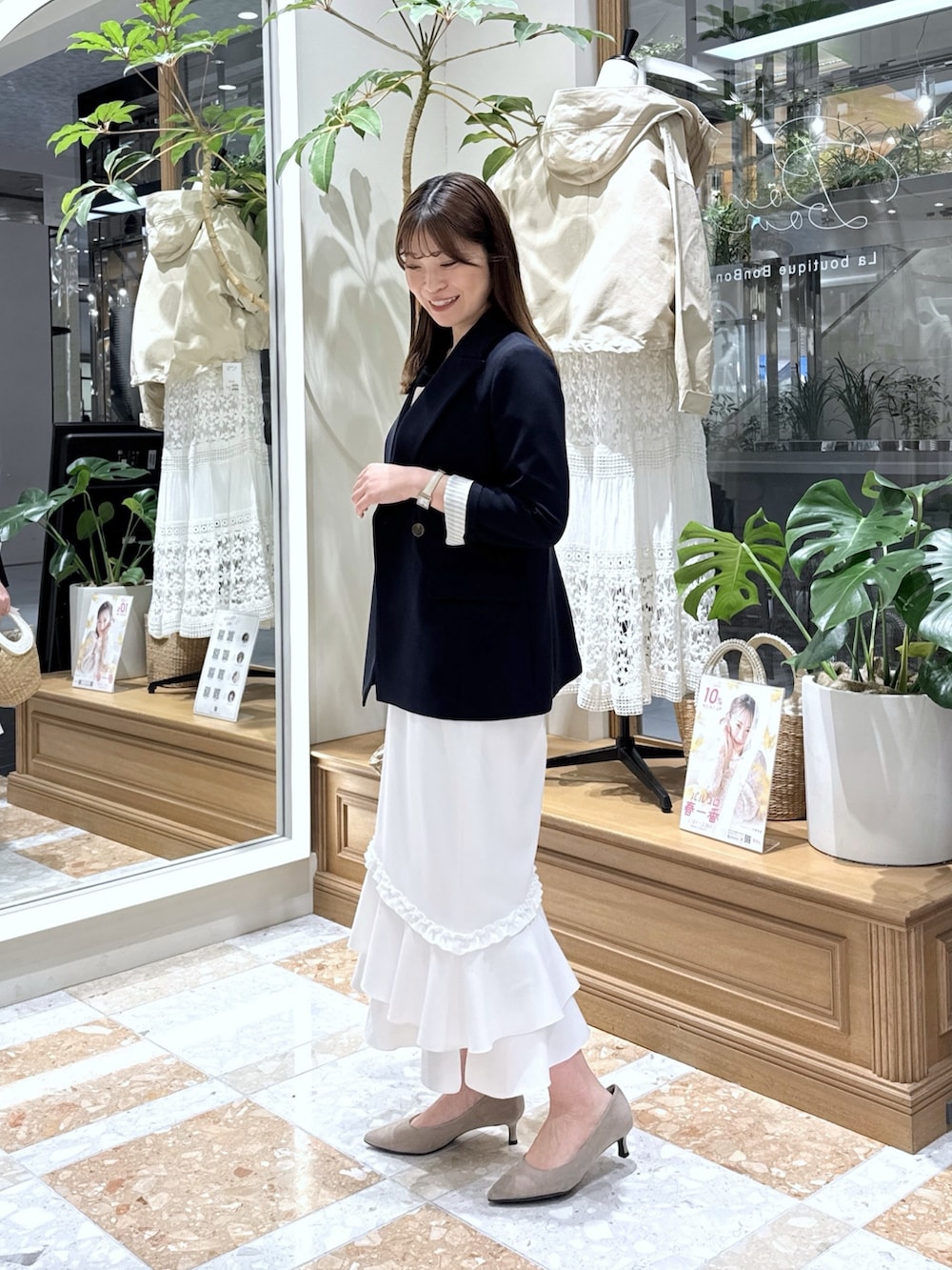 ブルー系のテーラードジャケット、ベージュ系のタンクトップ、ホワイト系のスカートを着用したレディースの冬コーディネートの2枚目の写真