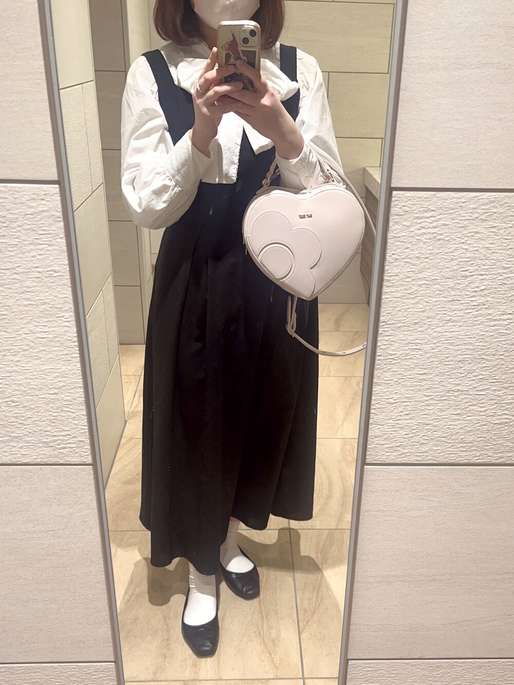 ホワイト系のバッグ、ホワイト系のシャツ/ブラウス、ブラック系のジャンパースカートを着用したレディースの冬コーディネートの3枚目の写真