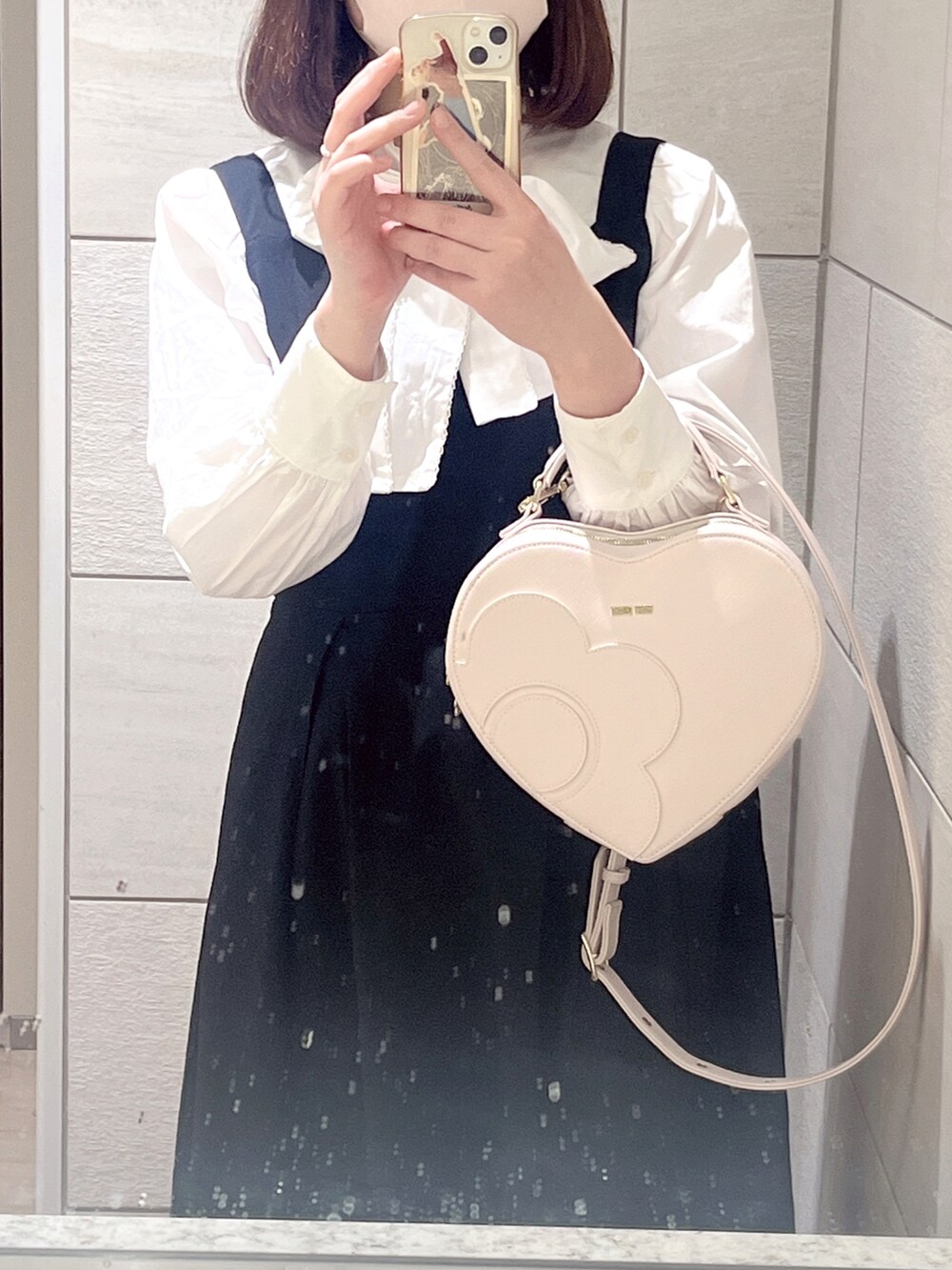 ホワイト系のバッグ、ホワイト系のシャツ/ブラウス、ブラック系のジャンパースカートを着用したレディースの冬コーディネートの2枚目の写真