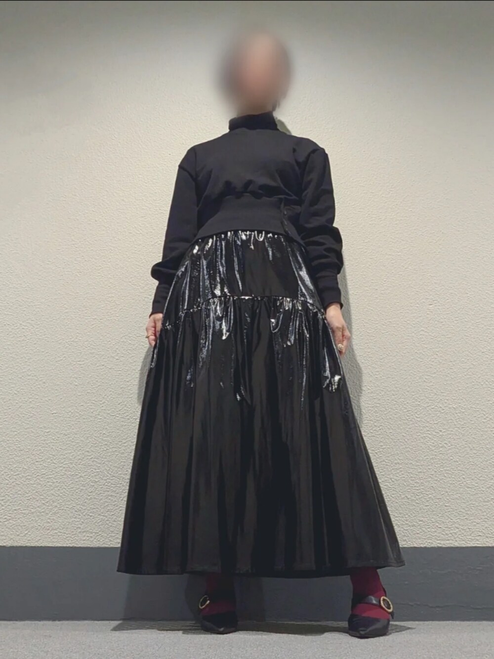 レッド系のトートバッグ、ブラック系のスカート、グレー系のポンチョを着用したレディースの冬コーディネートの2枚目の写真