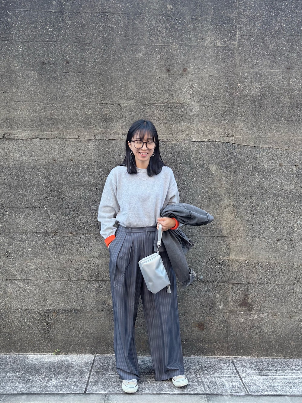 シルバー系のショルダーバッグ、グレー系のニット/セーター、グレー系のスラックスを着用したレディースの冬コーディネートの4枚目の写真