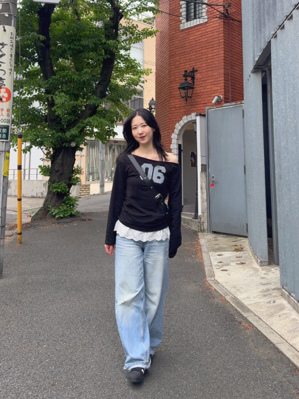 ブラック系のTシャツ/カットソー、ブルー系のデニムパンツ、ブラック系のスニーカーを着用したレディースの春コーディネートの3枚目の写真