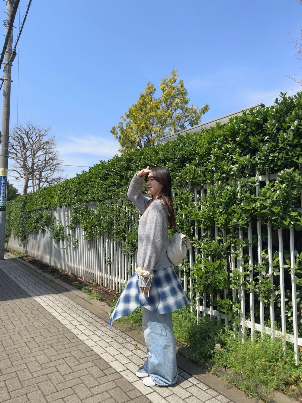 グレー系のニット/セーター、ブルー系のシャツ/ブラウス、ブルー系のデニムパンツを着用したレディースの春コーディネートの3枚目の写真