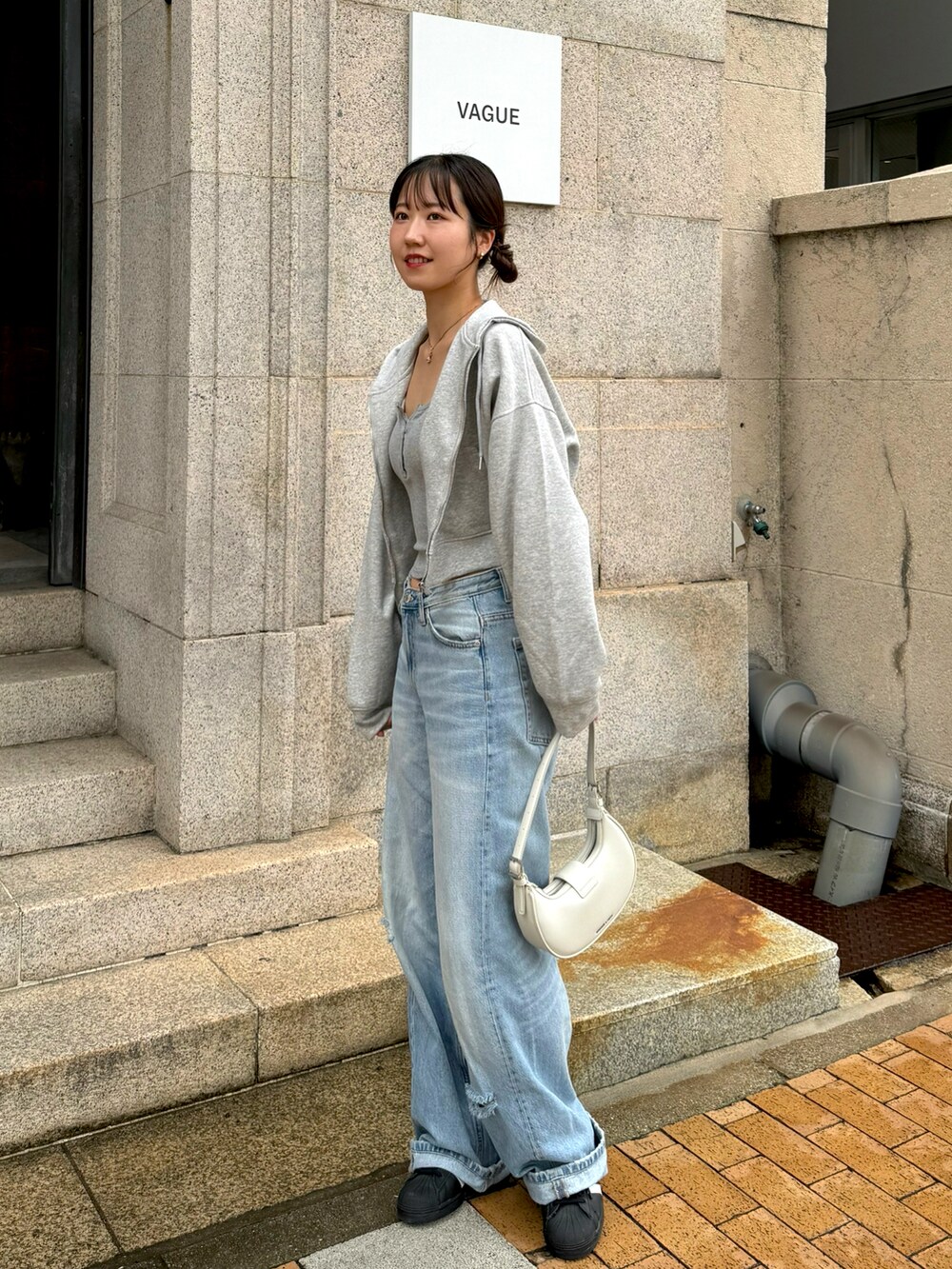 グレー系のキャミソール、ブルー系のデニムパンツ、ブラック系のスニーカーを着用したレディースの秋コーディネートの2枚目の写真