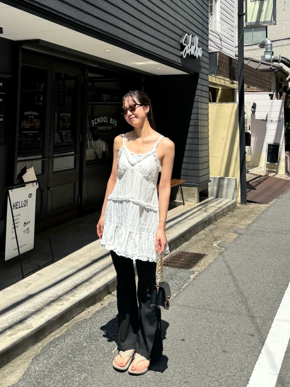 ホワイト系のキャミソール、ブラック系のデニムパンツ、ベージュ系のサンダルを着用したレディースの夏コーディネートの2枚目の写真