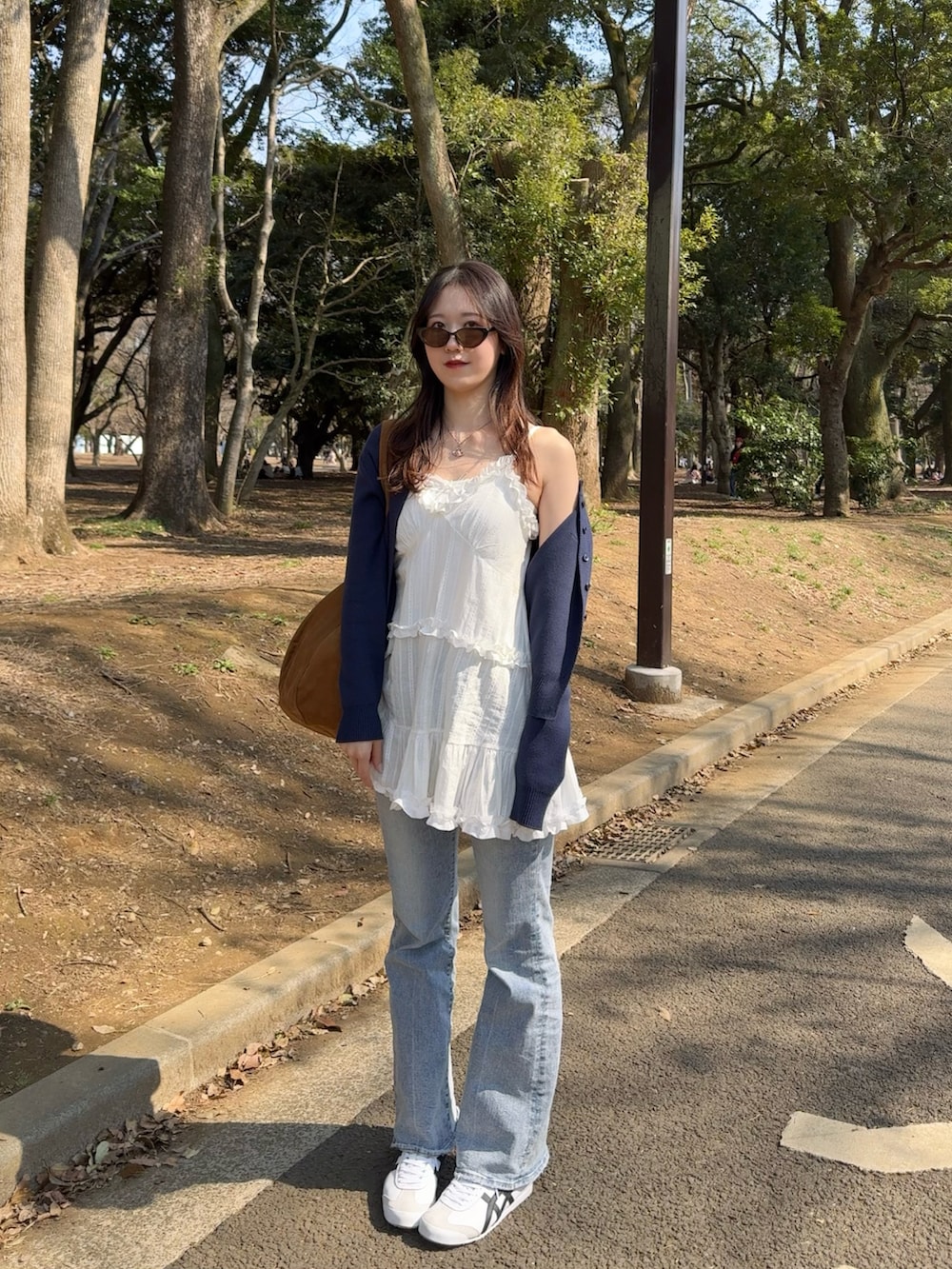 ホワイト系のキャミソール、ブルー系のデニムパンツ、ホワイト系のスニーカーを着用したレディースの春コーディネートの2枚目の写真